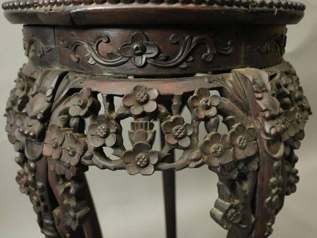 Antique Chinese plant stand features heavily caved hardwood with beaded border housing a marble inset and a pierced floral apron extending to five floral carved legs with rare pentagonal stretcher terminating in scaly paw feet, circa 1900.
  