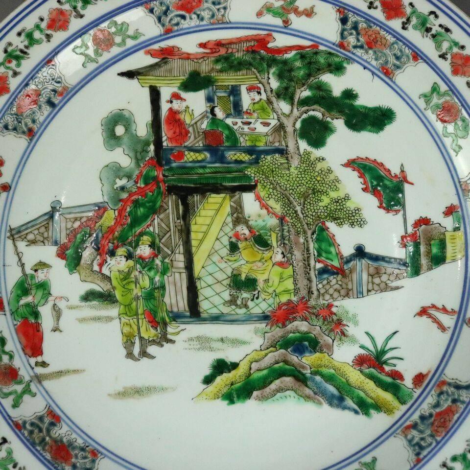 Antique Chinese canton polychrome porcelain charger has village scene with floral surround, circa 1910.

Measures: 17.25" diameter.