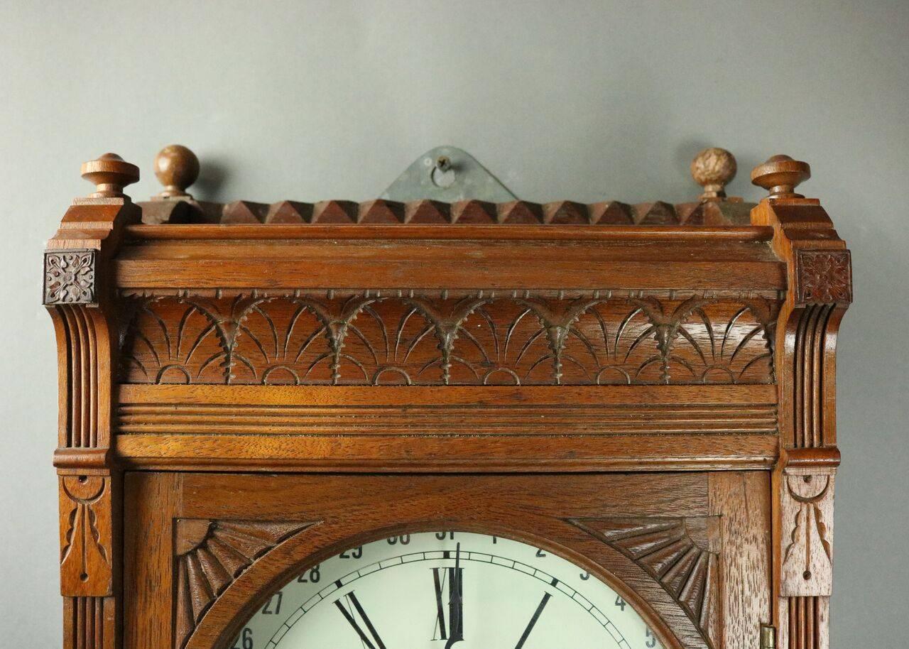 Antique German Seth Thomas type weighted regulator calendar wall clock feature Eastlake style walnut case with incised acanthus leaves, reeding and sunburst decoration and corners terminating in button finials, circa 1880. 

Clock is in working