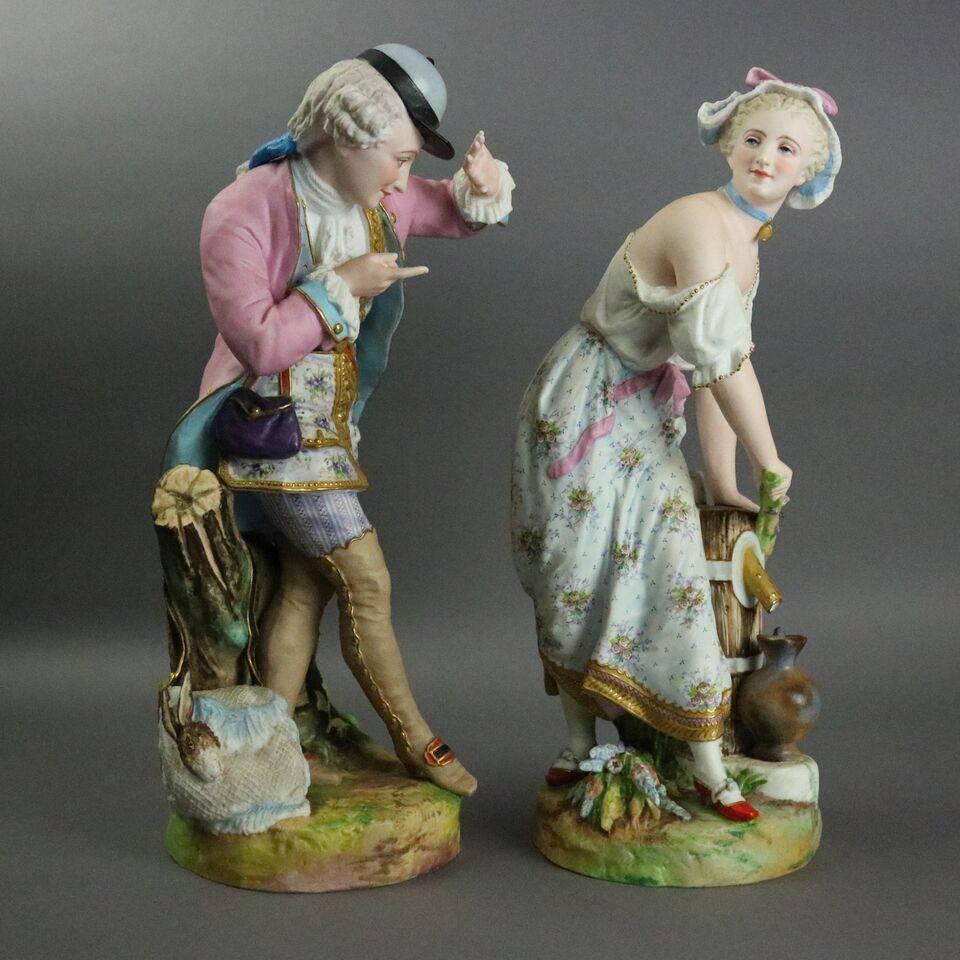 Antique hand-painted pair of English bisque porcelain figurines feature detailed hand-painted polychrome and gold decoration depicting courting couple in a countryside setting including a woman drawing water from the well and a visiting gentleman