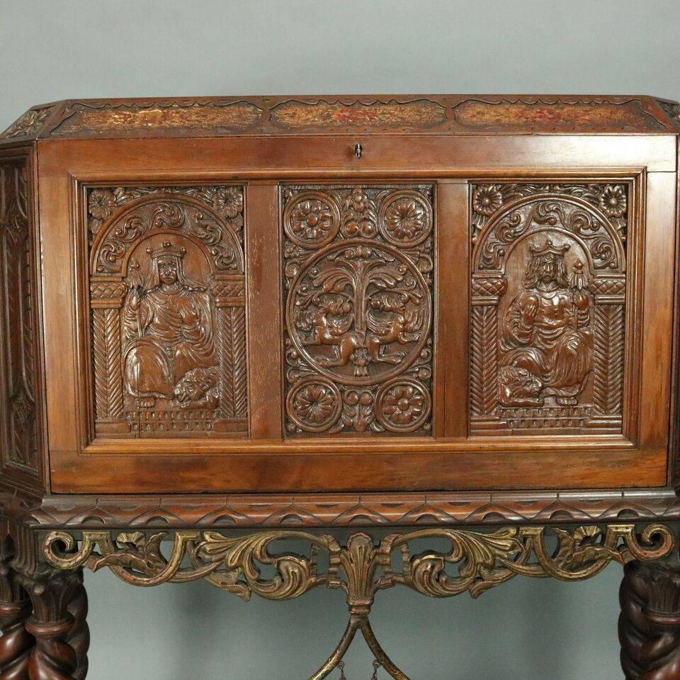 Antique English Jacobean style figural drop front desk features hand-painted coat of arms on opposing side panels, floral sprays in recessed panels along upper edge, heavily carved front panel with central hunt scene flanked by seated regal figures