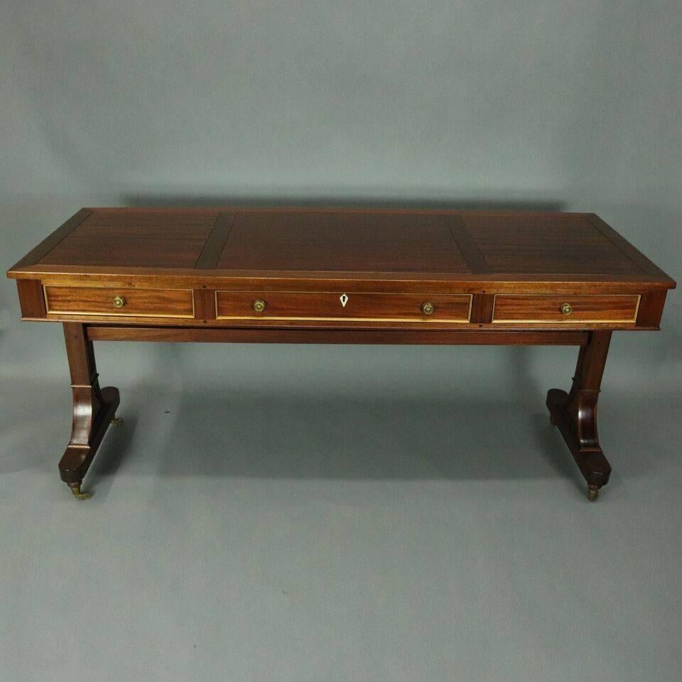 Vintage English George III style desk features mahogany construction with three drawers, bronze hardware and bone escutcheon, 19th century.

Measures: 30