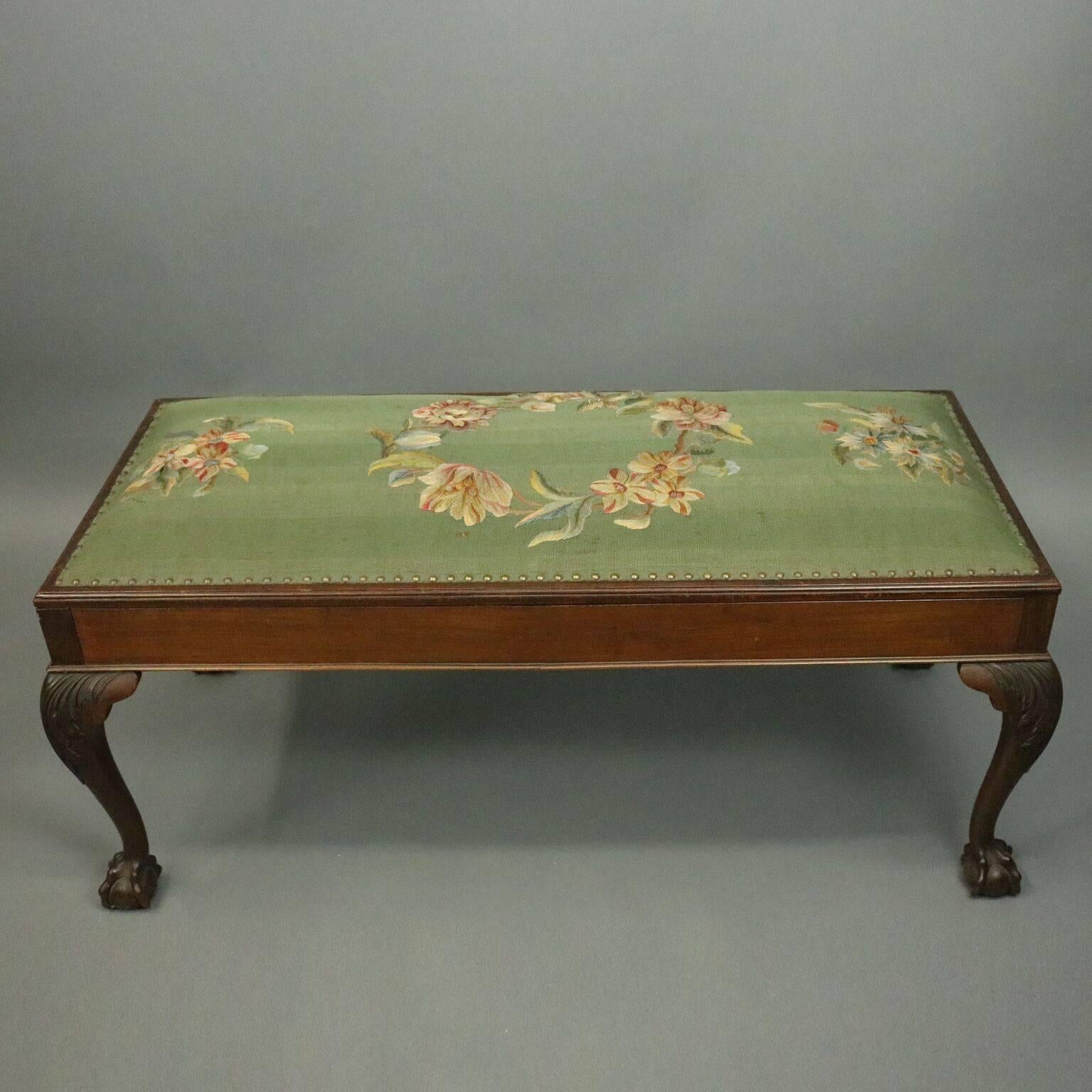 Antique Chippendale style lang bench features mahogany construction with cabriole legs with knees of carved acanthus leaves terminating in claw and ball feet, topped with floral needlepoint seat which opens to reveal an interior storage compartment,