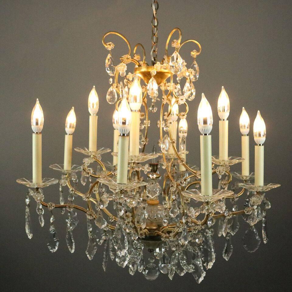 Vintage Venetian style chandelier features scrolled bronze twelve-arm frame lined with stylized floral and hanging crystals and crystal cased shaft, circa 1940

Measures: 29