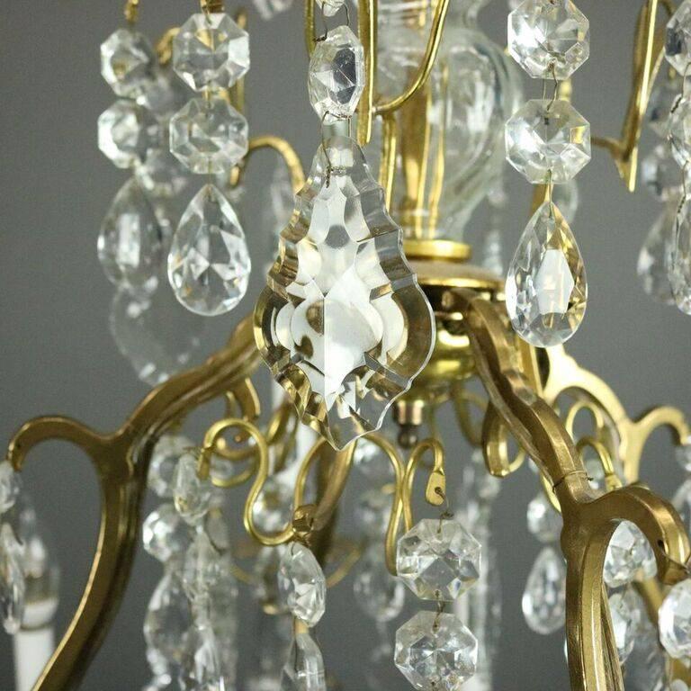 Oversized antique Louis XV style chandelier features bronze scrolled frame with 12 lights decorated with strung and drop cut crystals, circa 1900.

Measures: 38