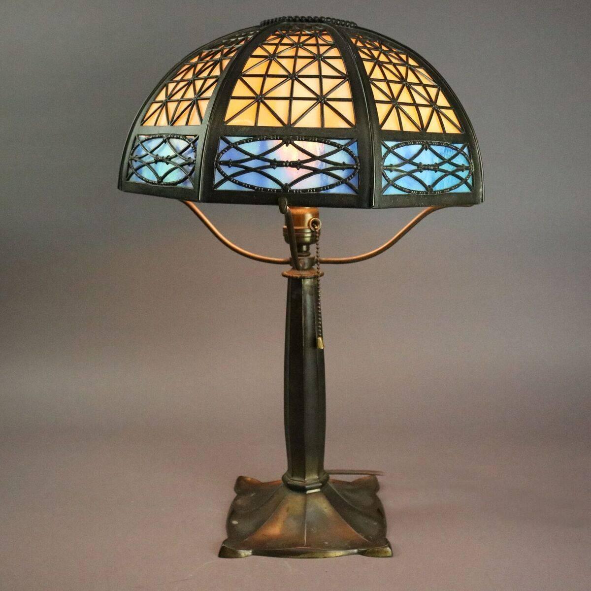 Antique Bradley and Hubbard Arts and Crafts table lamp features an eight panels of cream and blue slag glass in criss-cross pattern bronze frame supported by bronze base, B&H stamp on base, circa 1920

Measures - 22" height x 13"