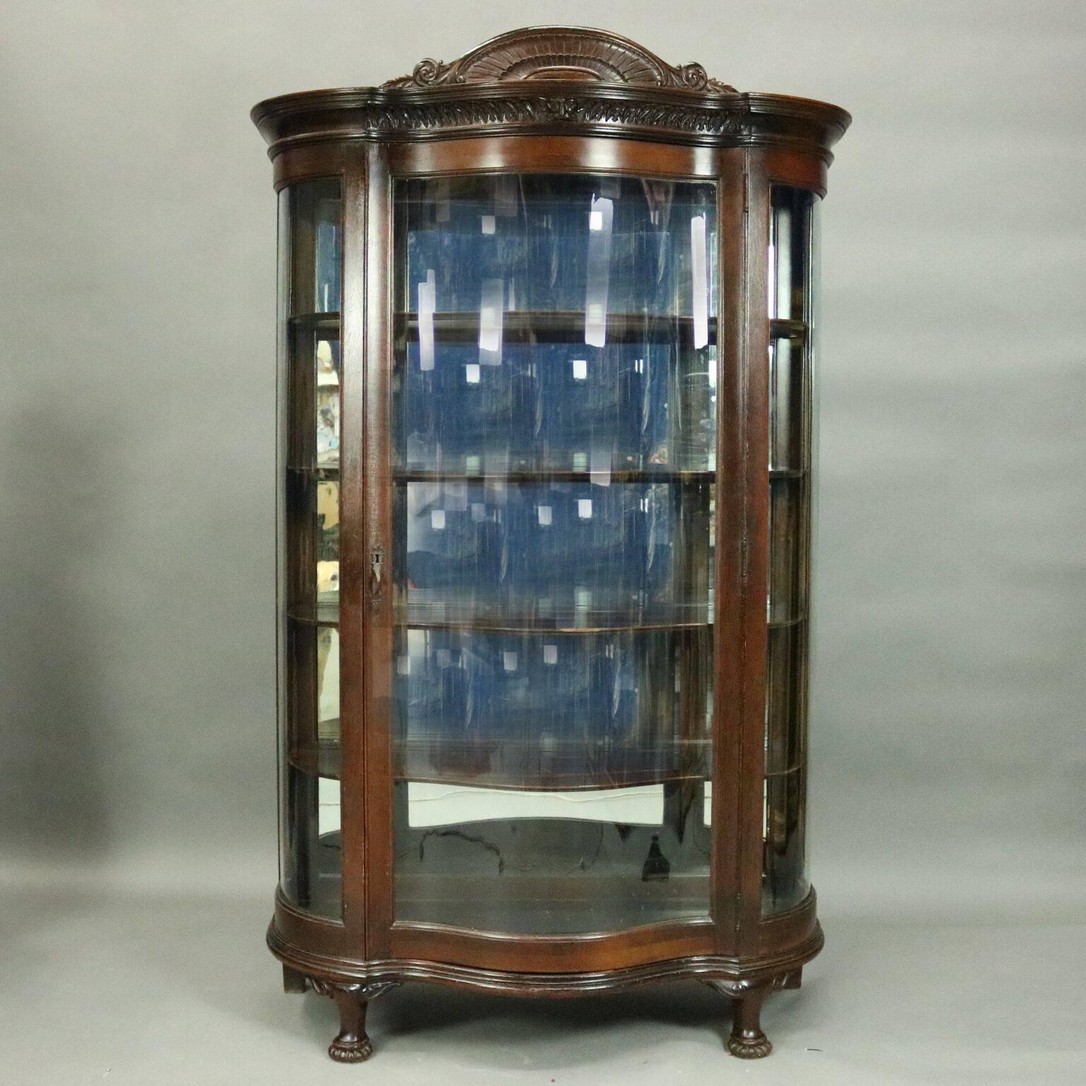 Antique dark stained oak Horner Bros. china cabinet features curved glass door and sides, carved molding and crest with figural mask, mirror back interior with four shelves, case seated on paw feet, circa 1900

Measures - 63.25" H x 47"
