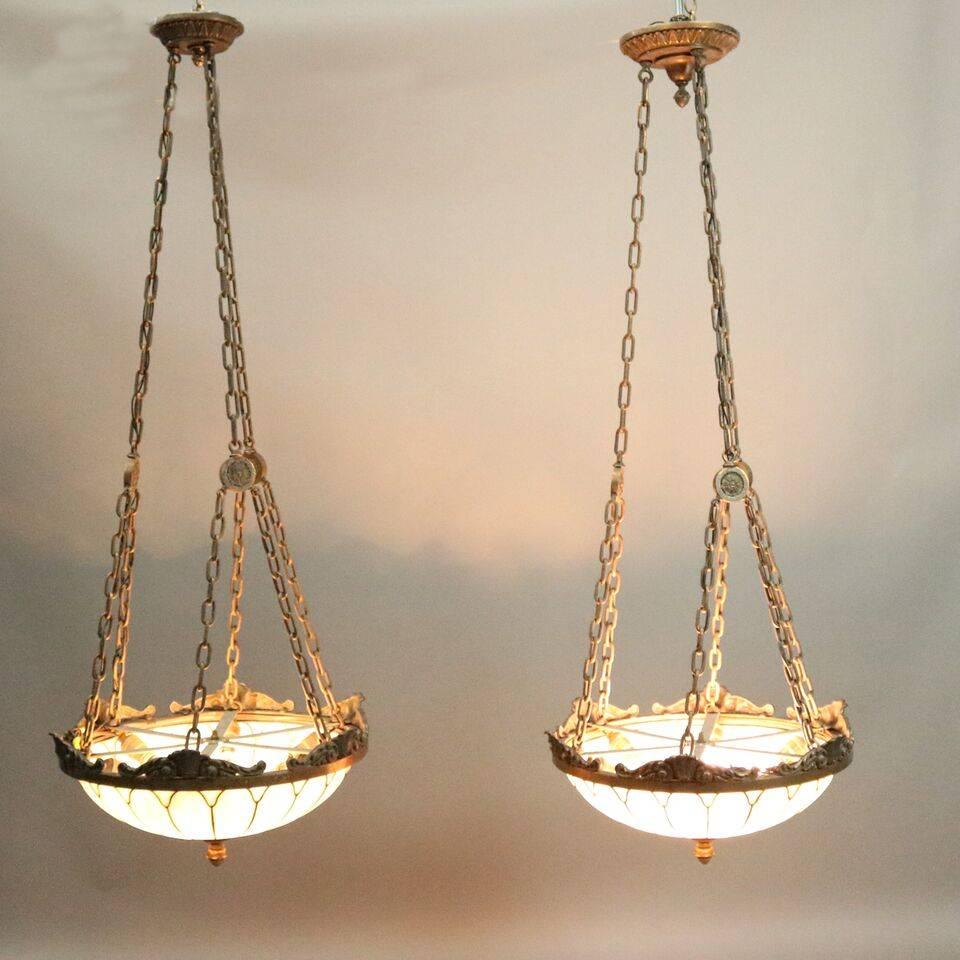 Pair of antique Arts & Crafts hanging dome lights feature cast bronze frames with acanthus and shell decoration suspending leaded glass domes with bronze finial, newly re-wired, circa 1910.

Measure: 60" drop x 22" diameter.