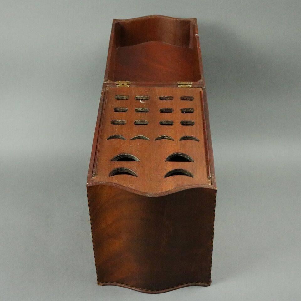 Antique Federal knife box features flame mahogany construction with serpentine front, edges of ebonized inlaid banding, central inlaid fluer de lis and removable interior knife tray, circa 1830.

Measures: 14.75" H x 8" W x 9" D.