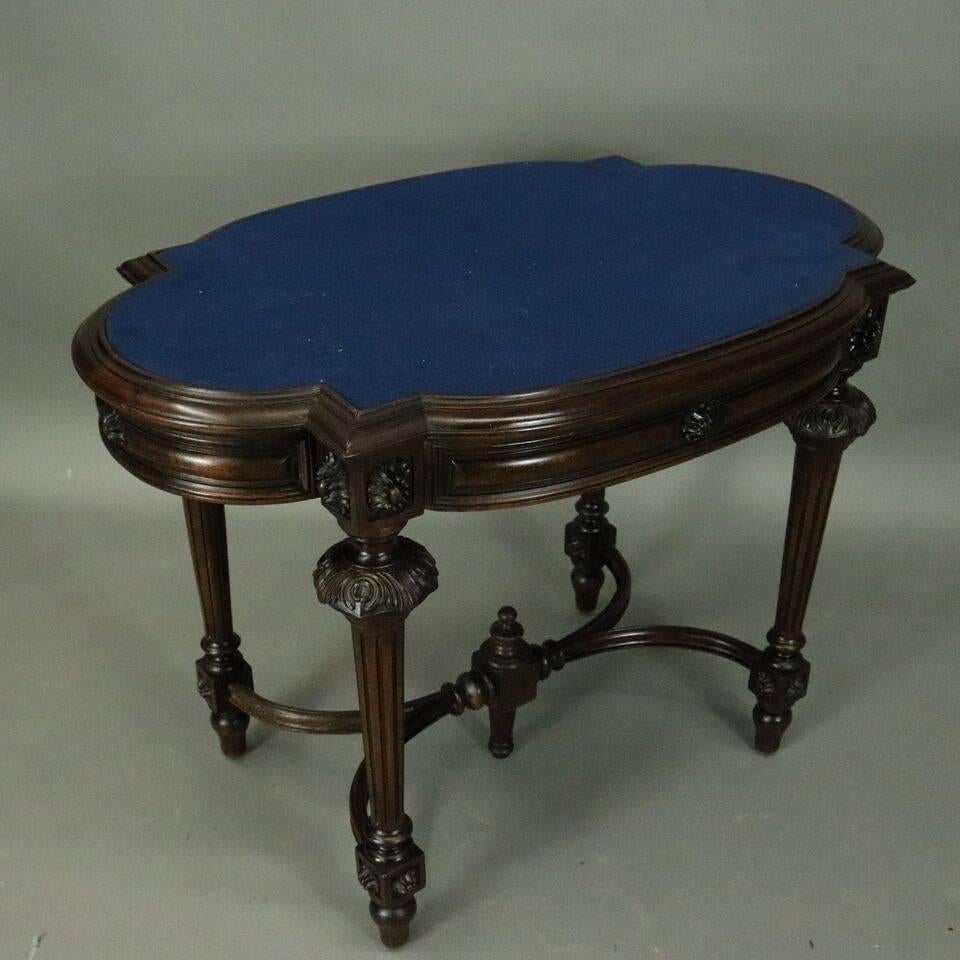 Antique French, Louis XIV style single drawer library table features walnut construction with stylized oval felt top, carved rosette die joints supported by tapered fluted legs capped by carved acanthus leaves, stretcher with central finial, circa