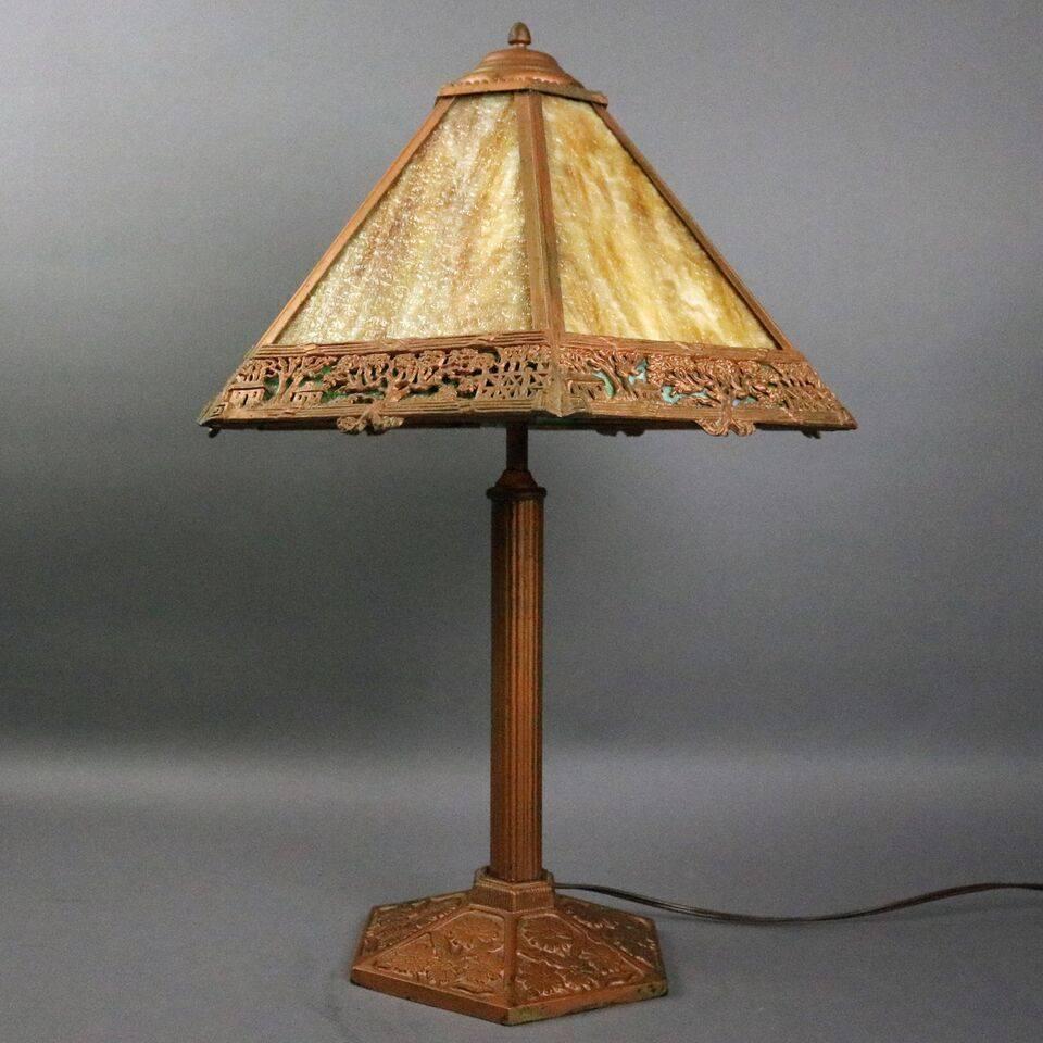 Antique Arts and Crafts Miller Co. Dual light table lamp features six-panel shade with slag glass housed in filigree shade, caramel glass over green border with countryside scene, base with reeded shaft and embossed floral foot, newly re-wired,