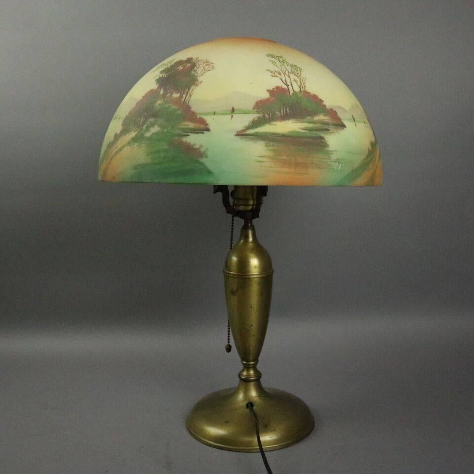 Antique Pittsburgh table lamp features brass base with obverse hand painted shade depicting lake scene, circa 1920

Measures: 20" height x 14" diameter (shade), 7" diameter (base).