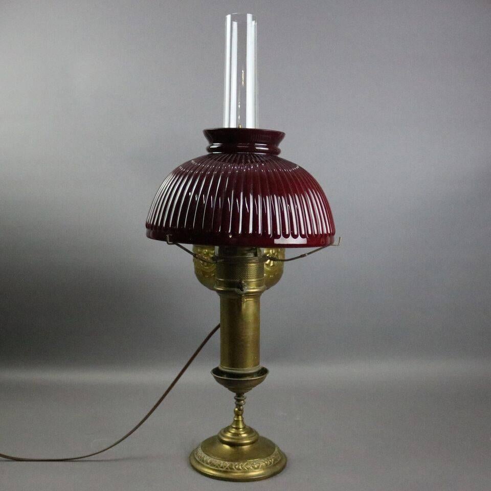 Antique student lamp by Miller Lamp Co. features brass frame, embossed font decorated with garland swags and fans, cast foliate finial, ruby shade, electrified, newly re-wired, circa 1880.

Measures: 21.5" H x 10" W x 6.5" D,