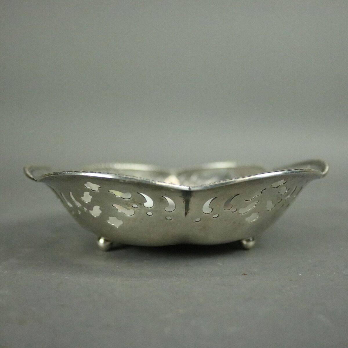 Antique sterling silver candy or ring dish features beaded scalloped edges, six reticulated sides, three ball feet, monogrammed center, Tiffany & Co. makers mark stamped on base, circa 1930

Measures: 1.5" H x 5/75" diameter.