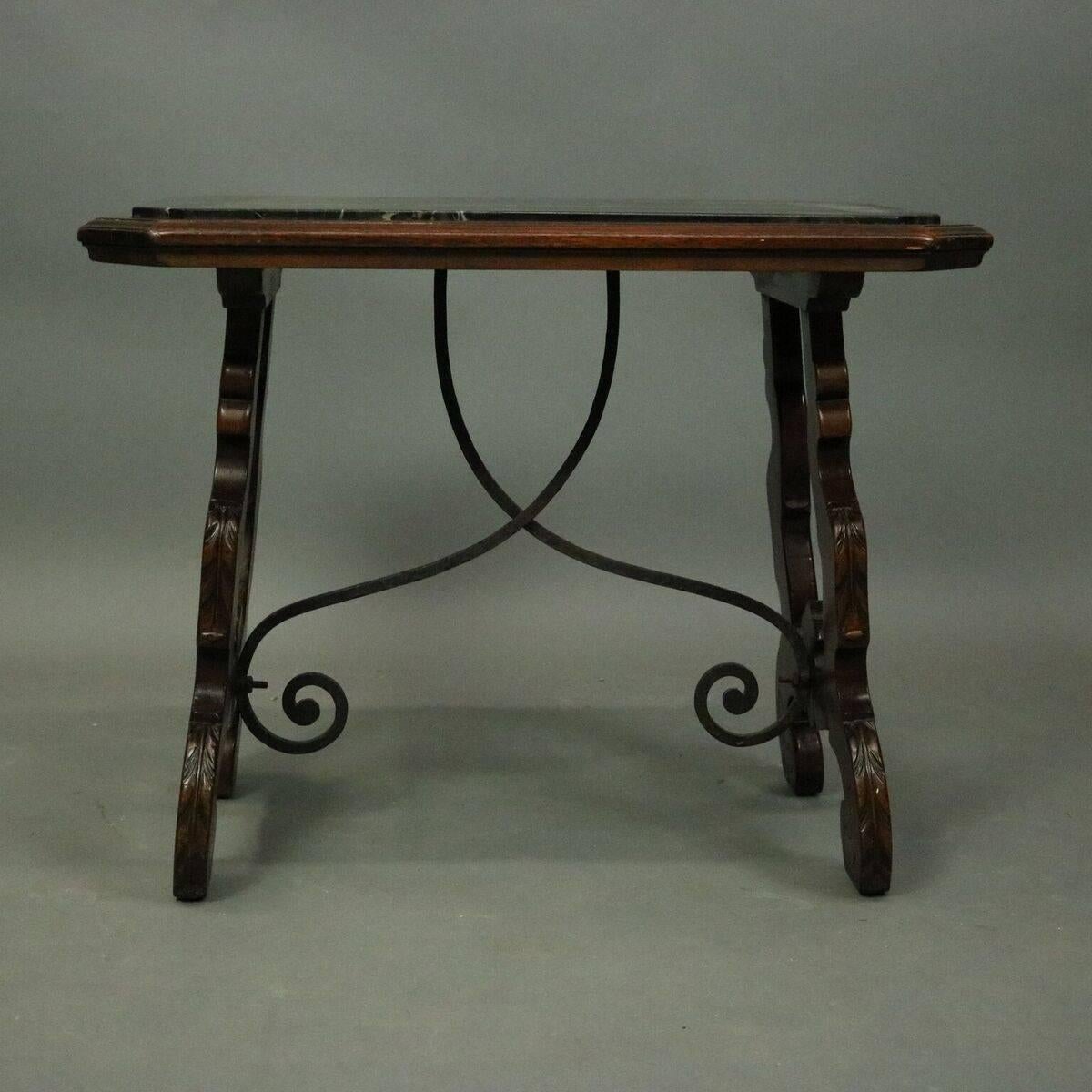 Vintage Continental coffee table features mahogany construction with acanthus carved trestle legs connected by scrolled wrought iron stretcher and picture frame black marble top, circa 1900

Measures: 20" H x 26" W x 17" D.