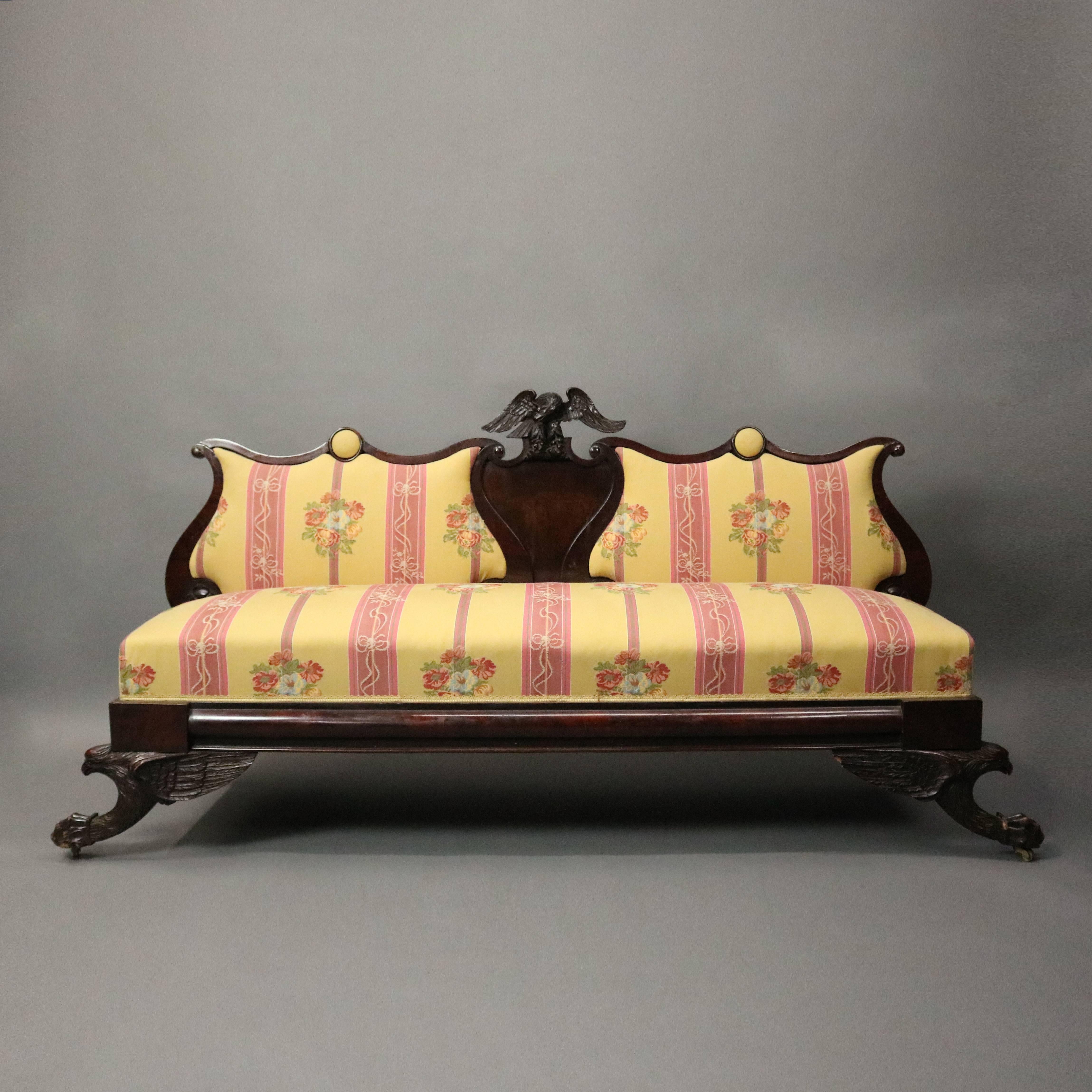 Antique American Empire sofa or settee features mahogany construction with highly detailed carved figural eagle legs and crest, triple shield shaped back, overall damask upholstered, reminiscent of Anthony Quervelle's work, circa 1820

Measures: