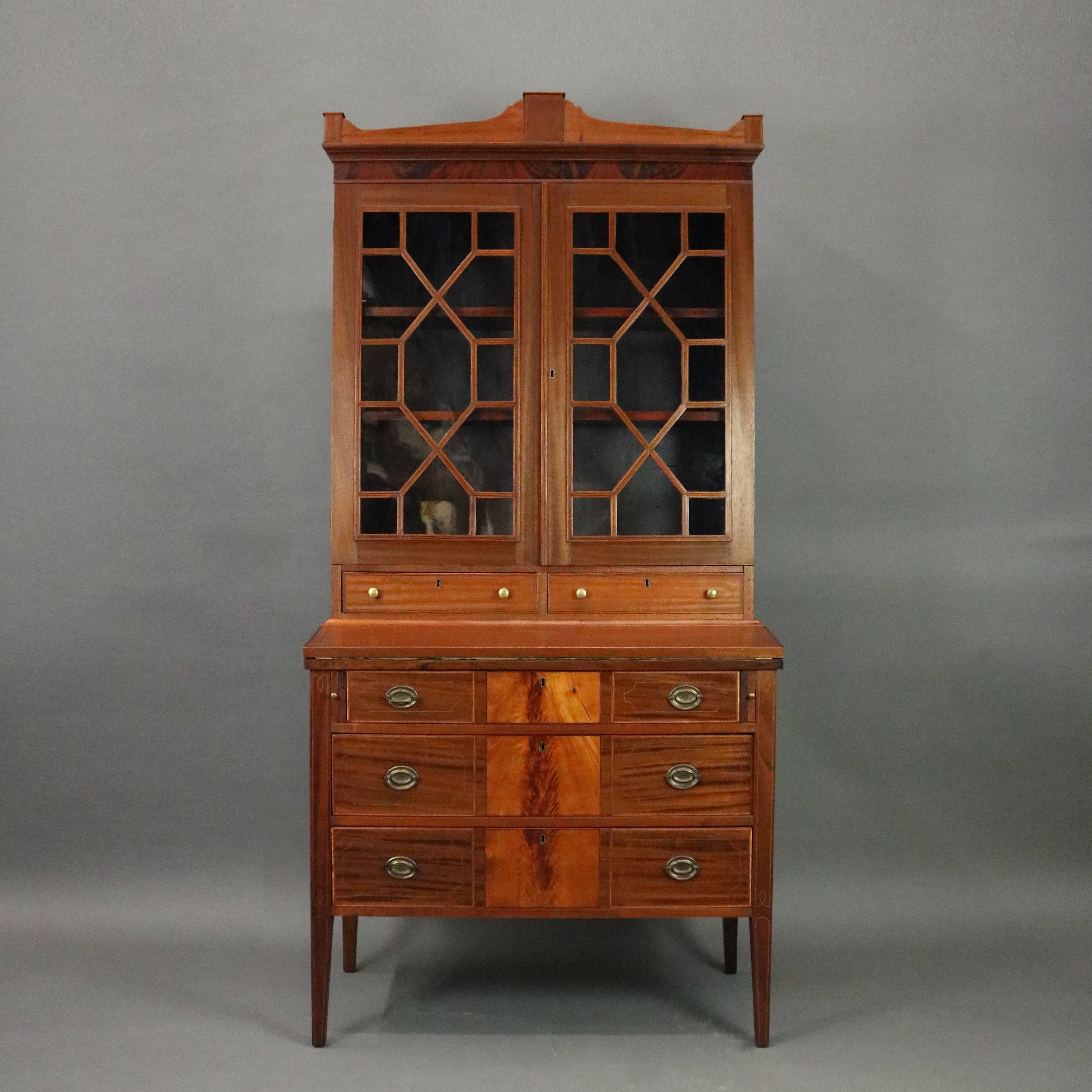 Antique American Federal secretary bookcase features mahogany construction with long drawers with flame mahogany insets below drop front writing surface opening to reveal storage drawers and pigeon hole compartments below glass front bookcase,