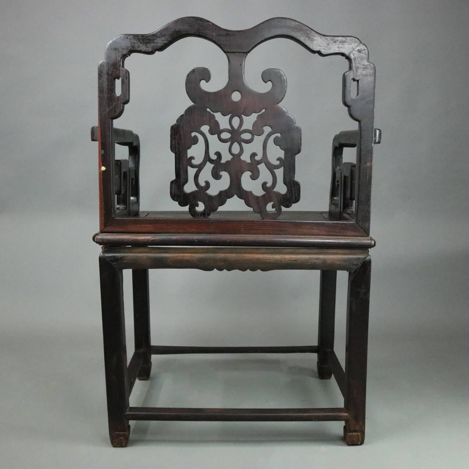 Antique Chinese throne chair features ebonized carved hardwood with pierced back with scroll and foliate floral design, circa 1890.

Measures: 38.75