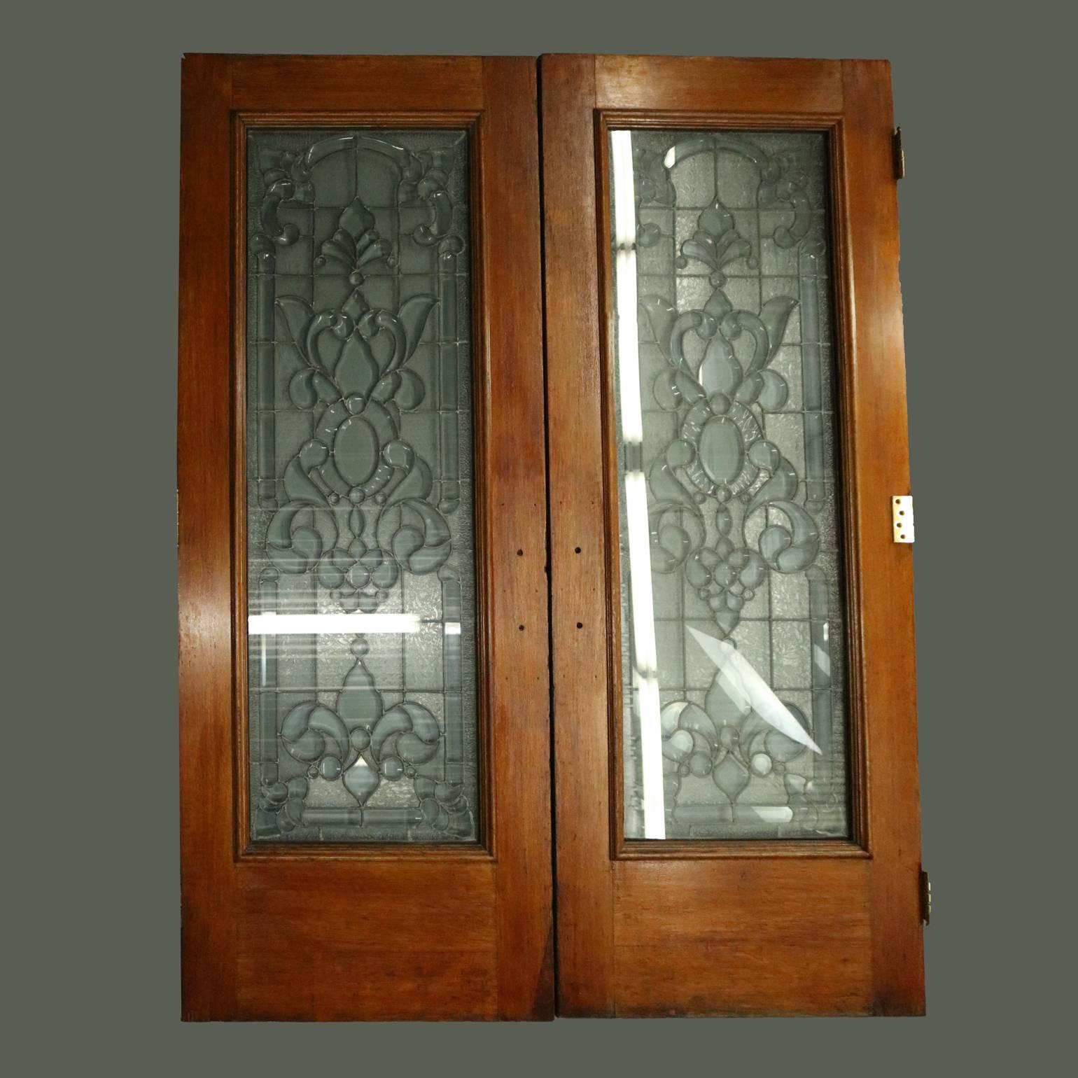 Antique pair of architectural leaded glass doors feature beveled glass in floral pattern seated in finished oak frames, circa 1920.

Measure - 82.75