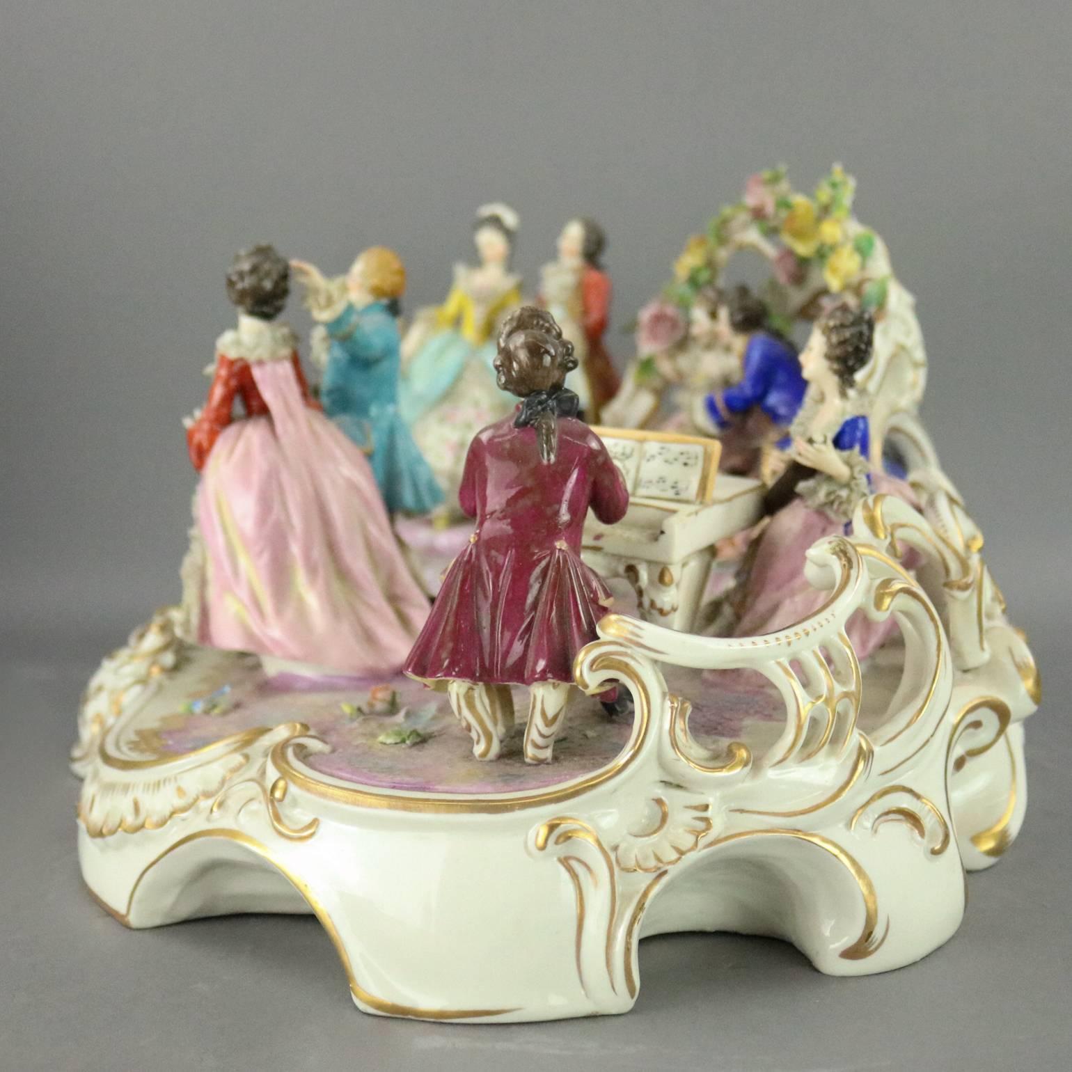 Antique German Dresden figural group features hand-painted and gilt grouping of ballroom scene with dancing figures and others playing musical instruments including mandolin and spinet piano, pierced backdrop, gilt scroll and foliate decoration