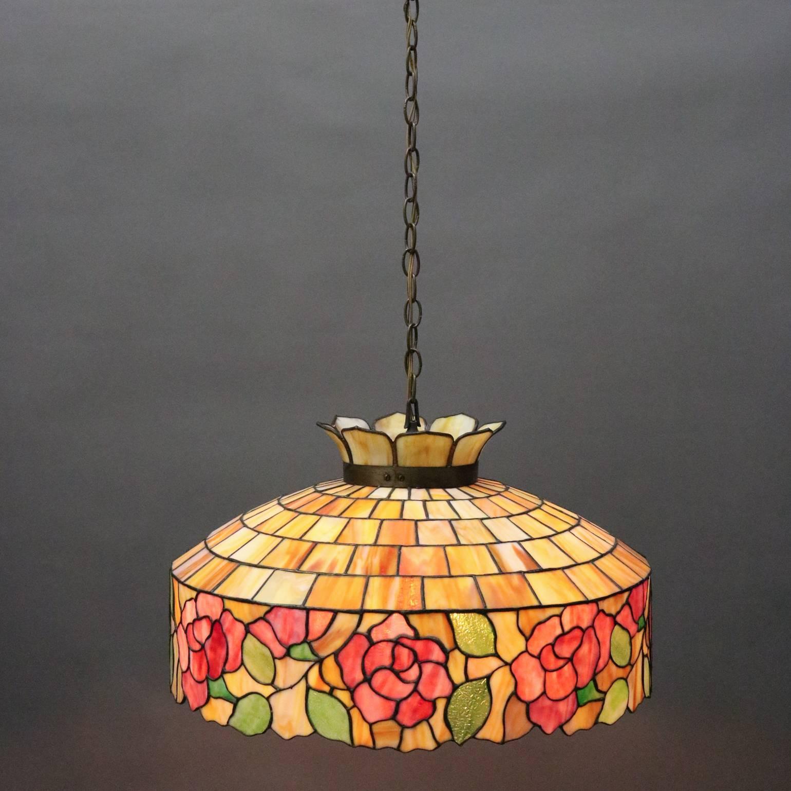 Antique Arts & Crafts Wilkinson school hanging light features leaded stained slag glass construction with floral rose decoration, circa 1920

Measures - 39" drop from canopy x 24" diameter x 16" H.