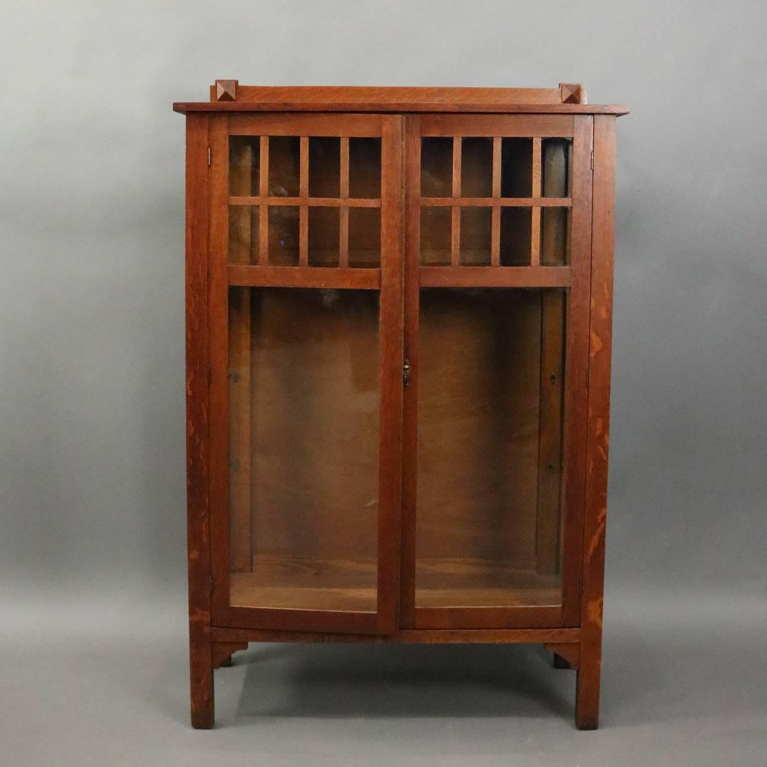 Antique Arts and Crafts Mission oak china cabinet features traditional simple and functional design with double glass doors with paneled upper opening to interior oak shelving, circa 1910

Measures: 61" H x 40" W x 16" D.