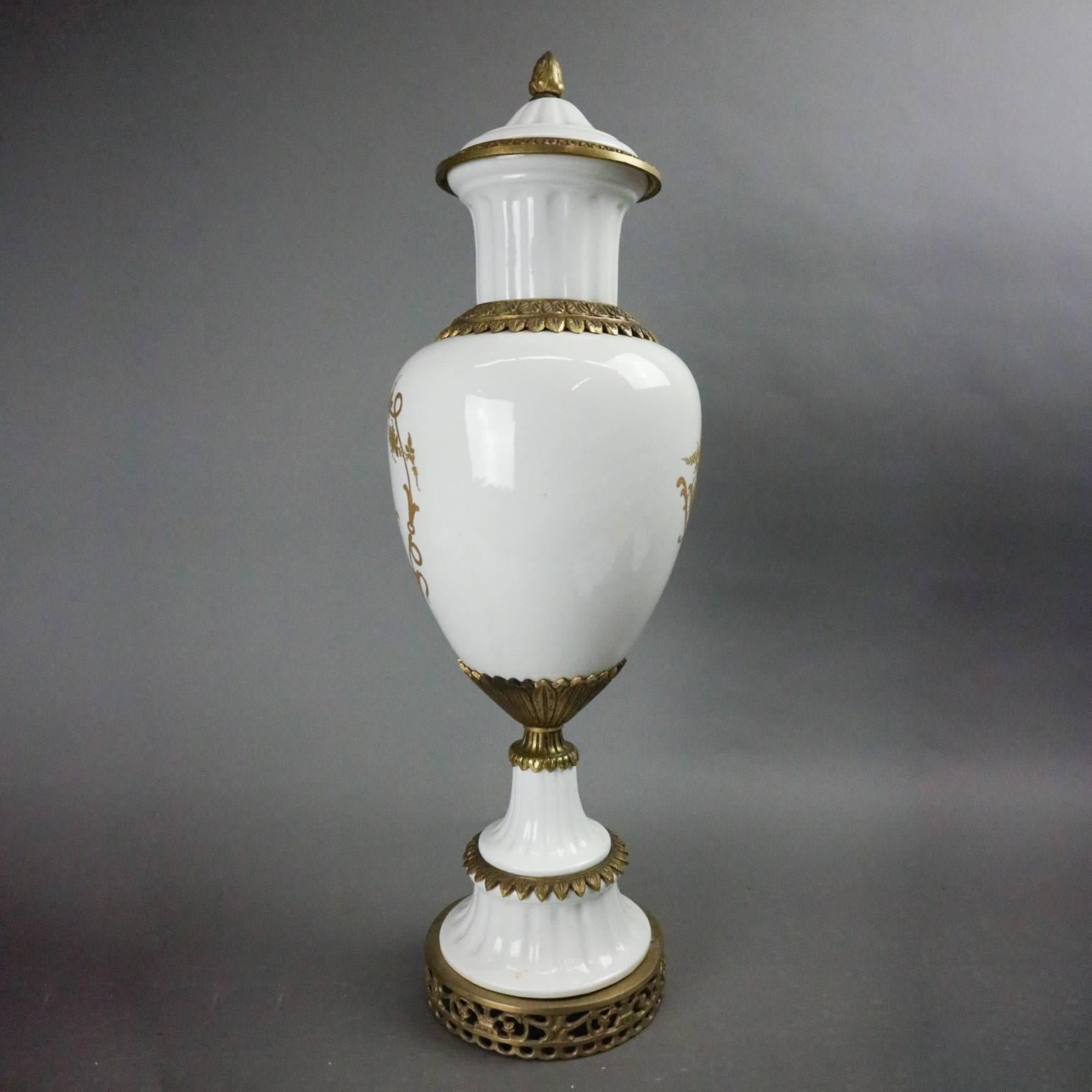Antique French Neoclassical porcelain urn features gilt foliate with musical instrument decoration and bronze accoutrements, artist signed Pierre Jusier with Sevres mark on base, circa 1940

Measures - 23" H x 8" diam.