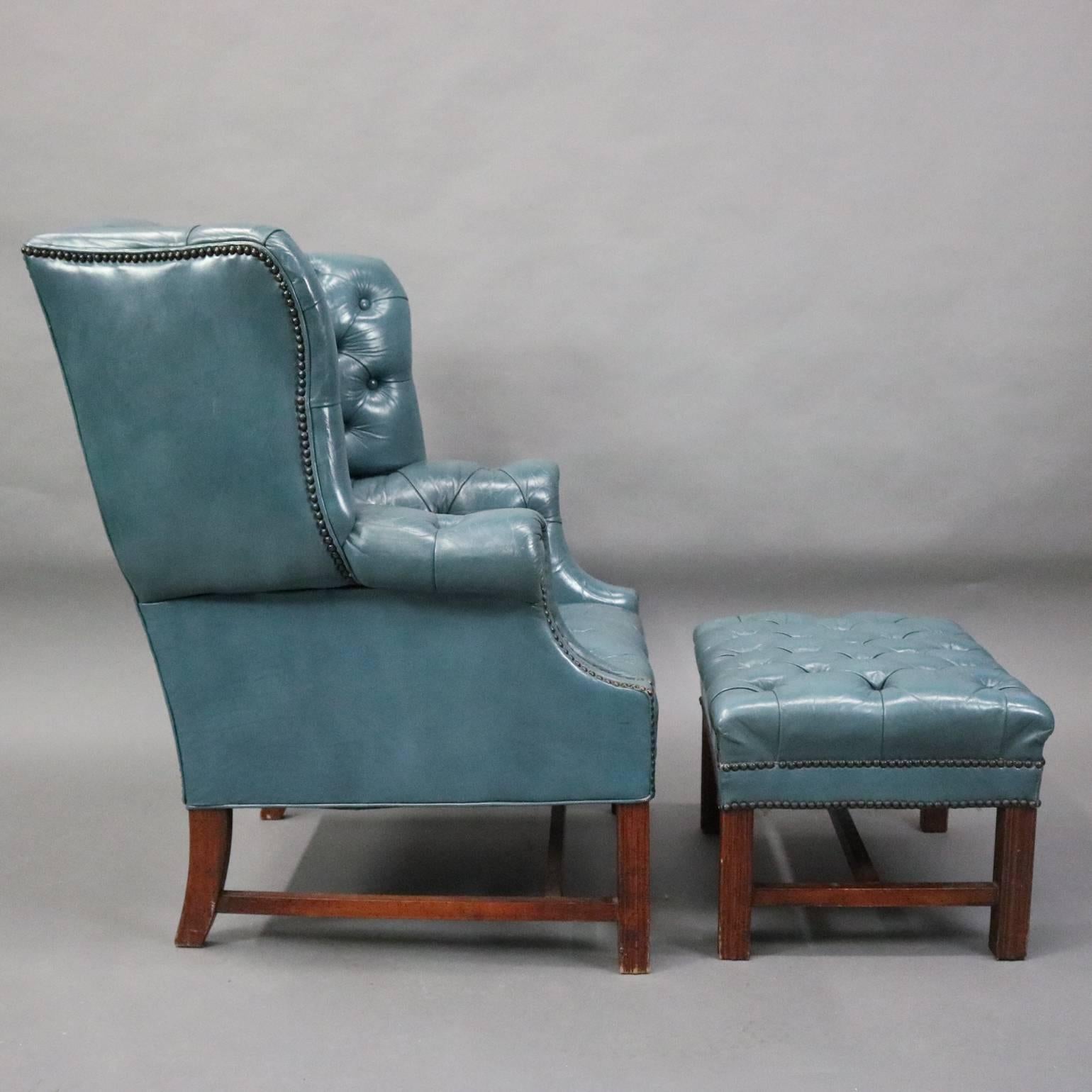 Vintage English Hepplewhite style Chesterfield wingback armchair and ottoman features button tufted leather upholstery and deep flared wings, circa 1960

Measures: 40.5