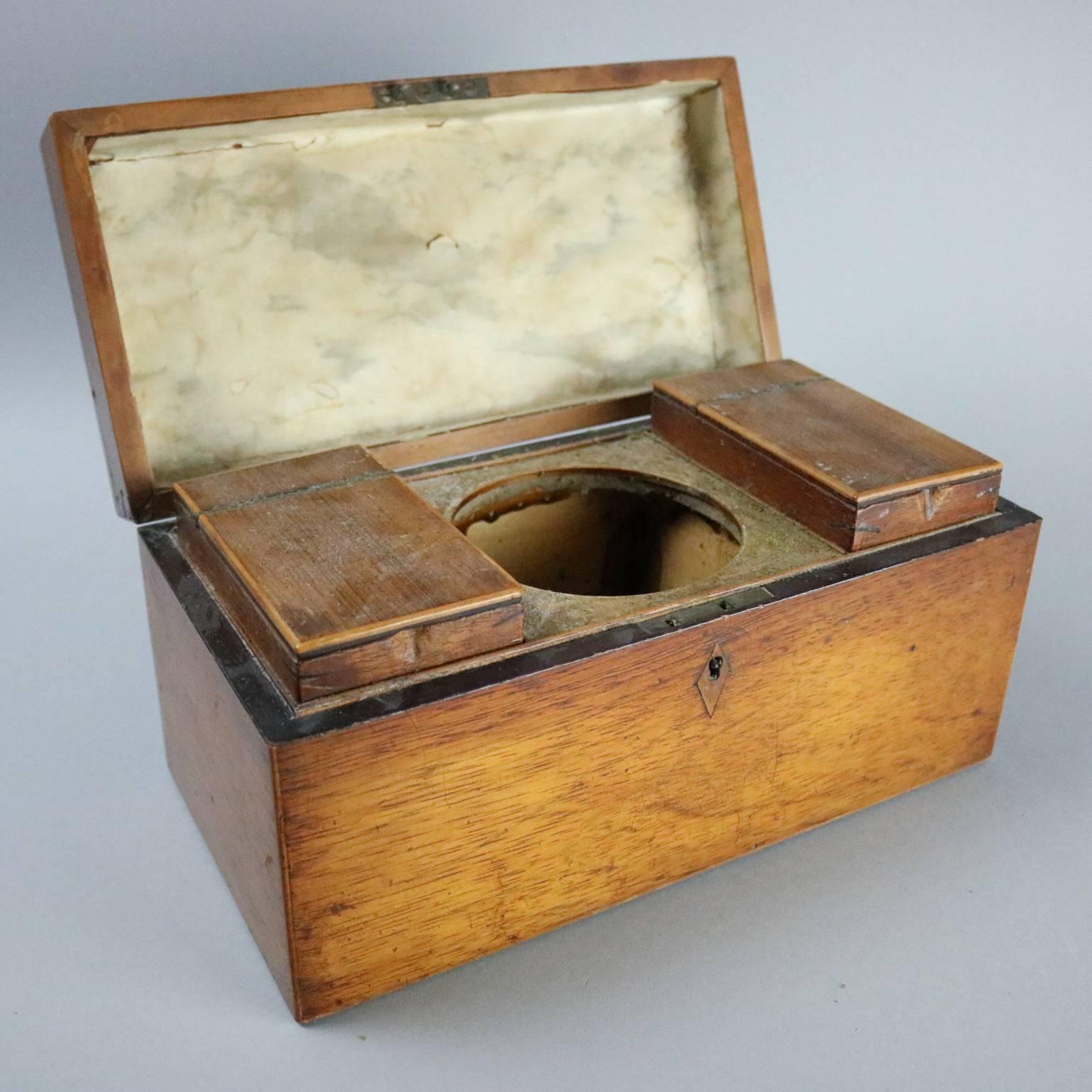 Antique English Georgian mahogany tea caddy features interior tea compartments, central waste compartment, inlaid escutcheon, circa 1870

Measures: 6" H x 12" W x 6" D.
