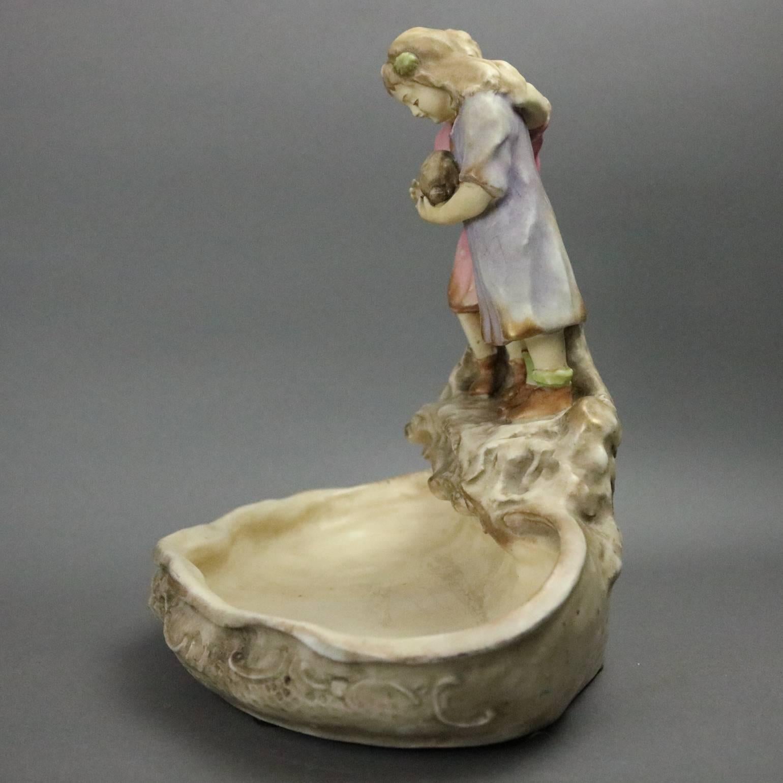 Antique Austrian figural Amphora Teplitz art pottery compote with children with their rabbit on the shore, maker's mark stamped on base, circa 1900

Measures: 10.5" H x 11.5" W x 7" D.