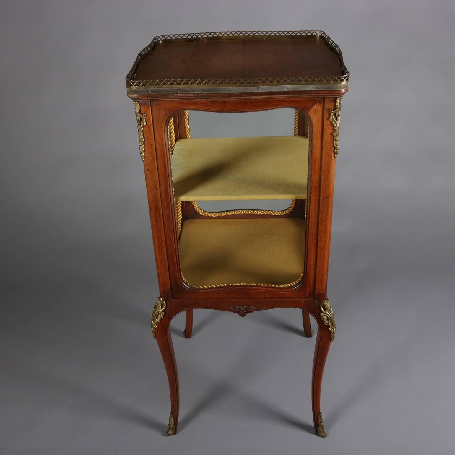 Antique petite French Louis XV style mahogany vitrine features delicate square form with foliate carved skirt and set on cabriole legs, decorated with cast foliate ormolu, pierced bronze gallery, and shelved lined interior, circa 1880.

Measures: