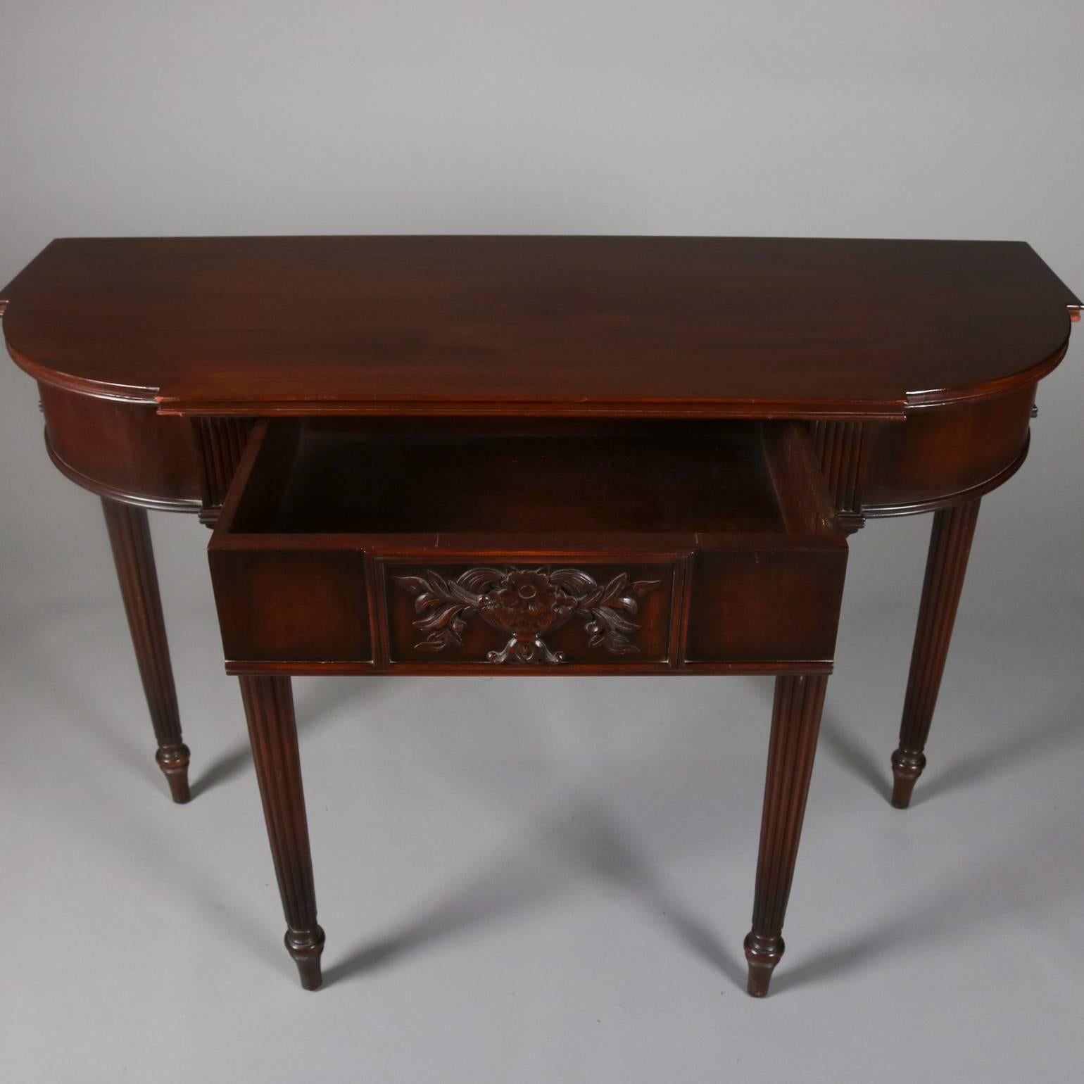 Antique carved mahogany console set by Elgin A. Simonds Company Furniture features console table, centre drawer with carved central floral basket bouquet and supported by reeded and tapered legs; mirror with cut-out and ebonized mahogany frame, en