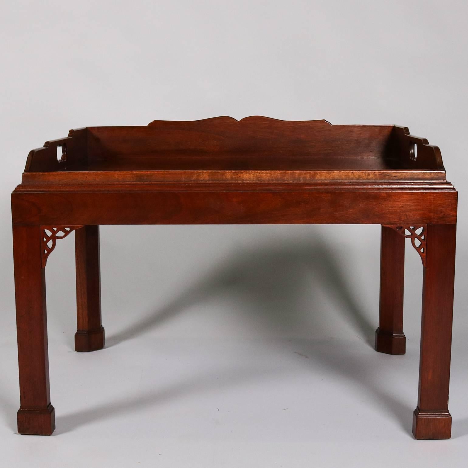 Antique carved mahogany tray top table by Baker features Chinese Chippendale form with pierced foliate corner and removable tray, 20th century.

Measures: 19