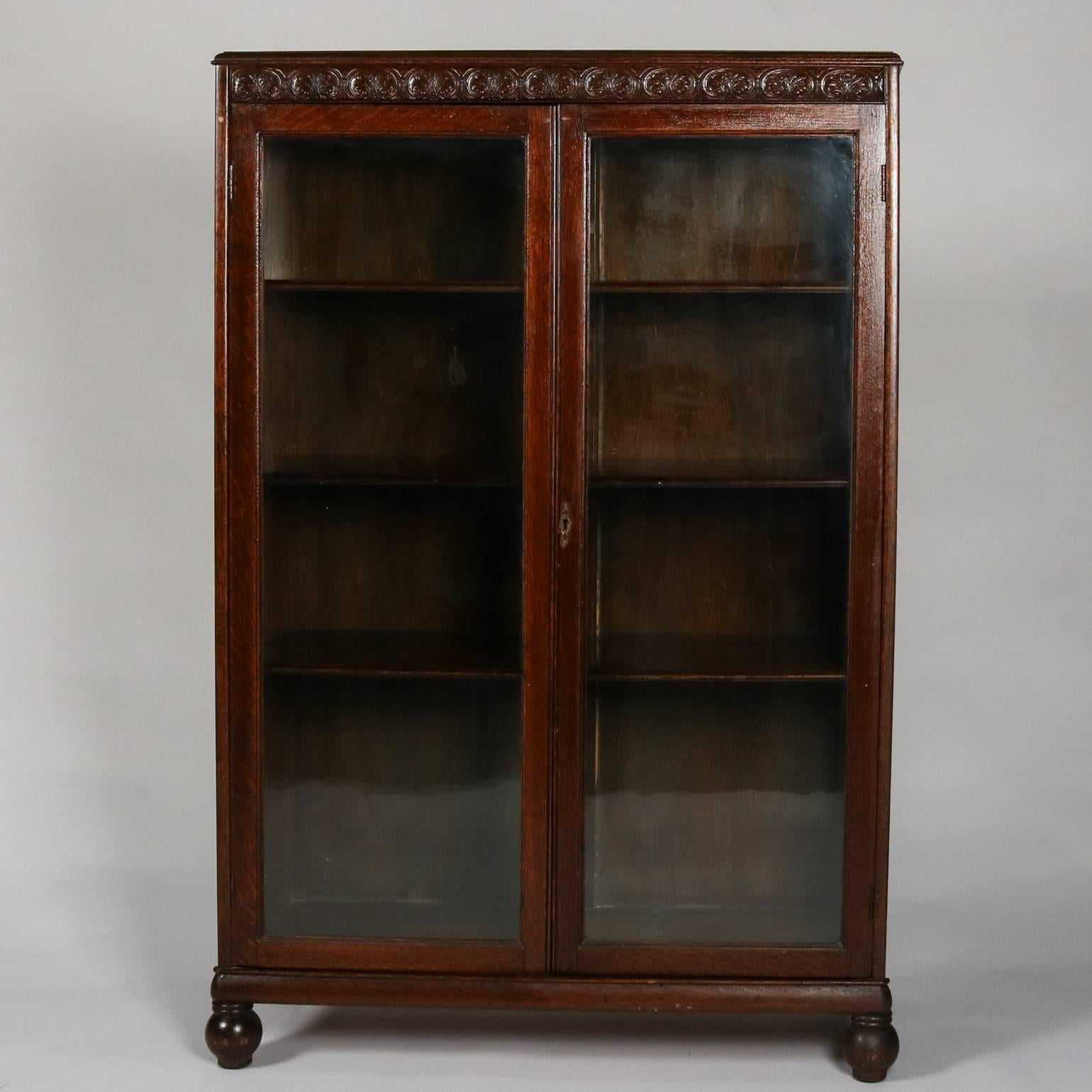Antique oak bookcase by Horner Bros. features carved scroll and foliate trim, two glass doors, interior shelving, and is seated on ball feet, 19th century.

Measures: 53.5" H x 35.5" W x 13.5" D.