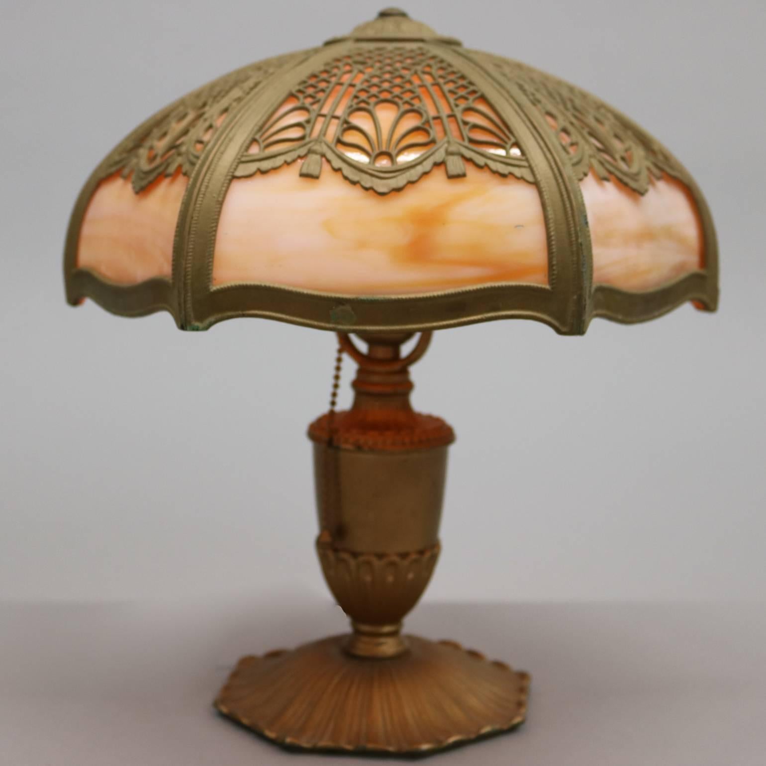 Antique Arts & Crafts junior size slag glass lamp by Miller & Co. features six panel filigree overlay shade with bronzed urn form base, E.M. & Co. and 1911 on base, early 20th century.

Measures: 13.5" H x 11.5" diam.