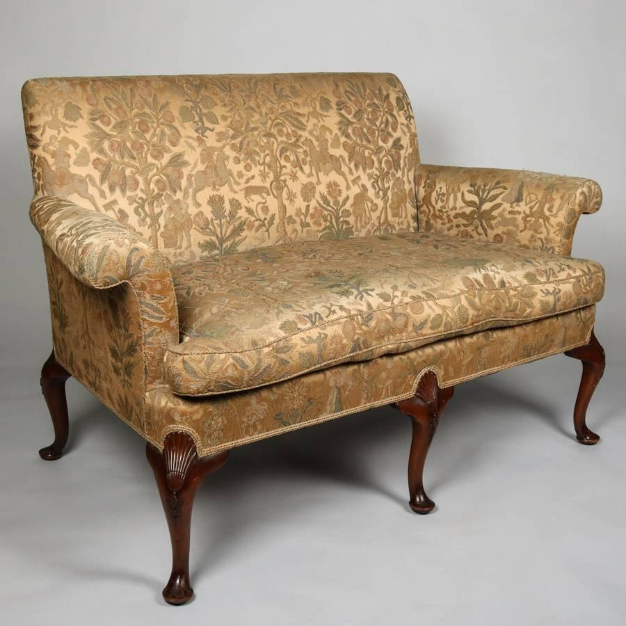 Antique Queen Anne settee features tapestry upholstery with hunt scene pattern, scrolled arms and carved mahogany cabriole legs, 19th century.

Measures - 35"H X 53"W X 28"D, 20" seat height.