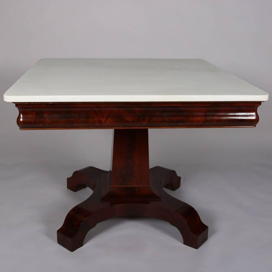 Antique American Empire center table features flame mahogany base with tapered plinth supporting marble top, 19th century.

Measures - 29"H X 38"W X 38"D.