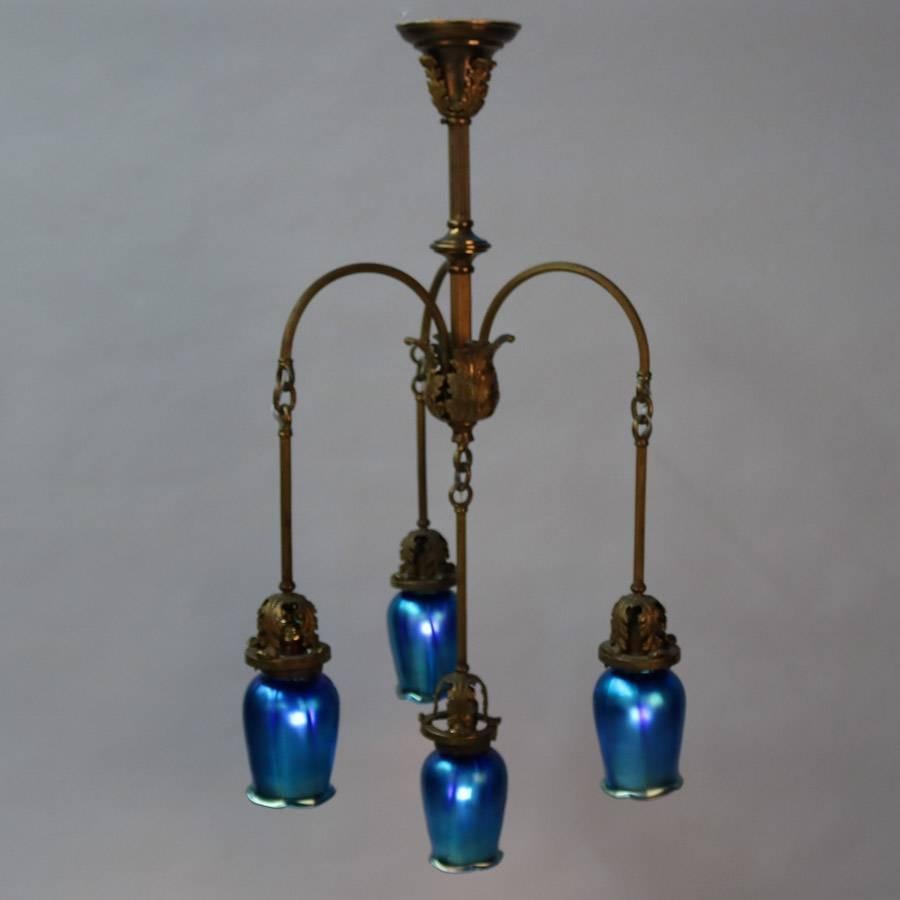 Antique Arts & Crafts four-light chandelier features four foliate drop arms terminating in newer blue Steuben Aurene School glass tulip form shades, newly rewired, circa 1910

Measures: 36" drop x 16" diameter.