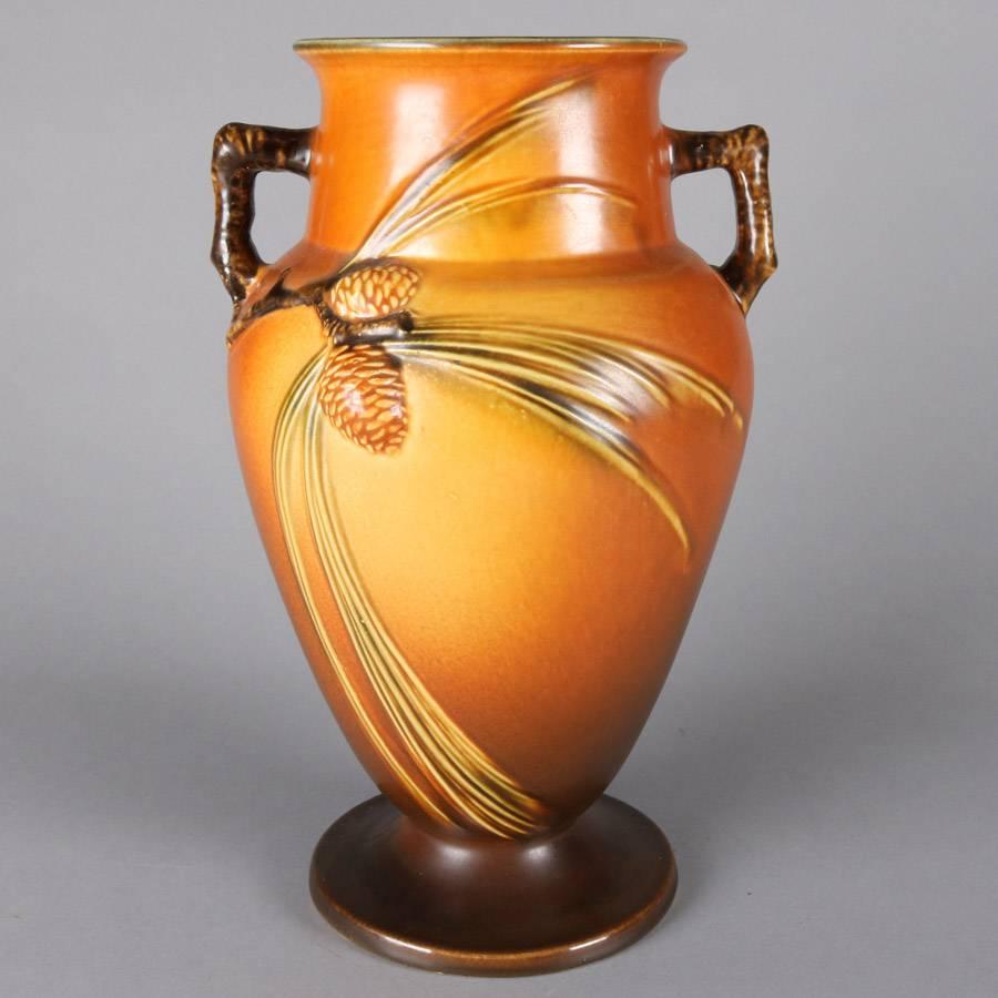 Roseville art pottery vase features double handle urn from in brown Pinecone pattern, label on base, 20th century.

Measures: 14.5