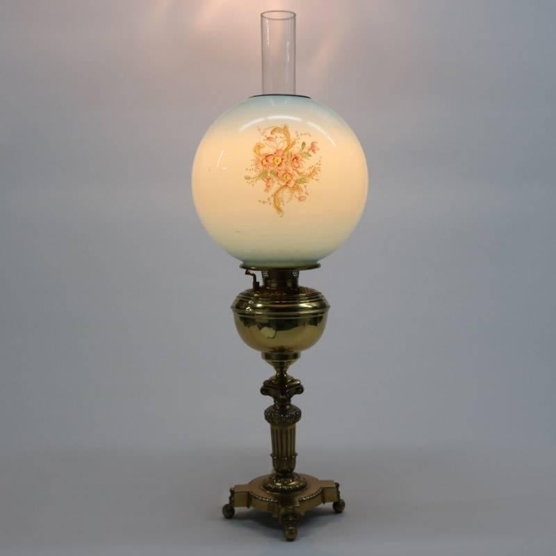 Antique gone with the wind lamp features cast brass base with reeded and shell Greek column pedestal seated on acanthus decorated base and ball feet, floral paint decorated globe, early 20th century

Measures: 29" H x 9" diameter.