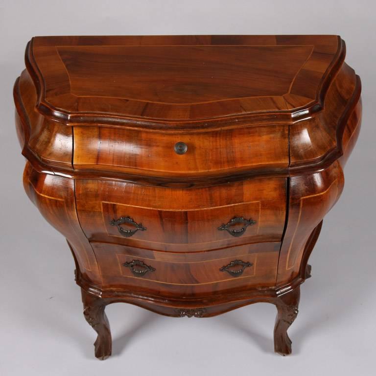 Italian flame mahogany stand features three drawers and satinwood banding throughout, seated on carved cabriole legs, en verso original "Made in Italy" label, 20th century

Measures: 27" H x 27" W x 14" D.