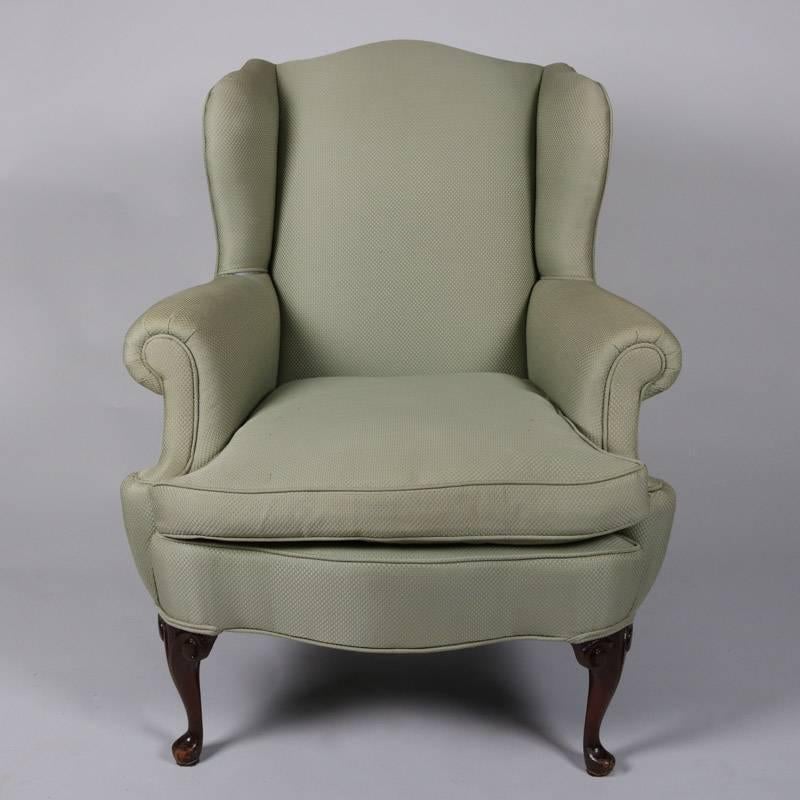 Pair of antique Queen Anne style wingback chairs feature scrolled arms and scalloped aprons in soft sage green upholstery, seated on mahogany legs, 20th century.

Measure: 40" H x 32" W x 28" D, 19" seat height.