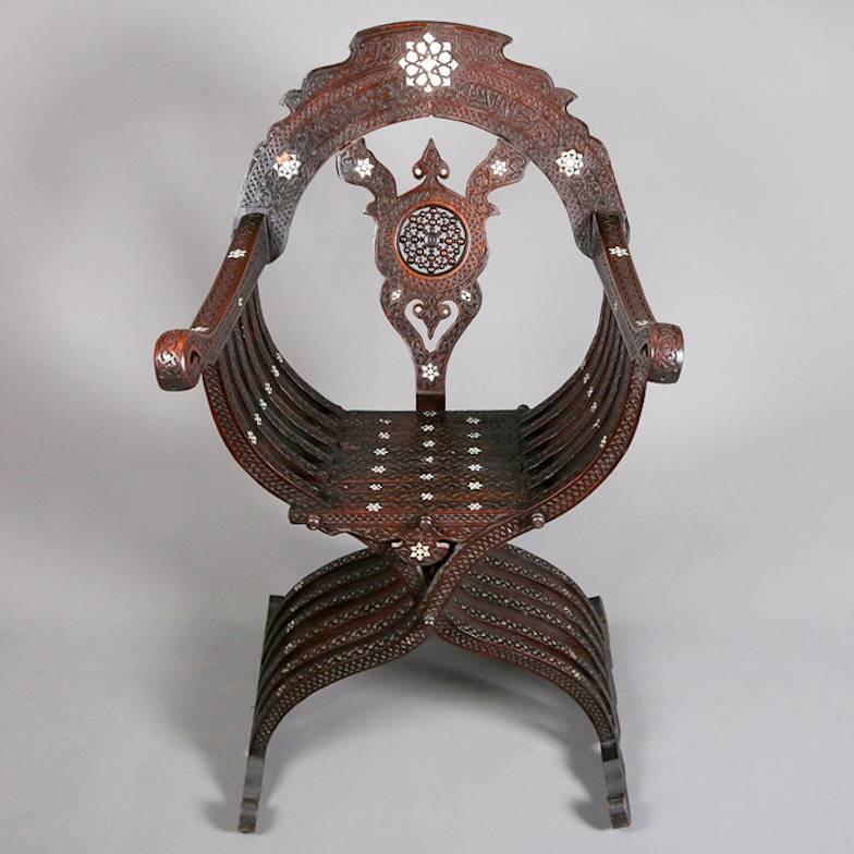 Antique and ornate Syrian or Turkish throne chair features curule form with inlaid mother-of-pearl in Star of David insets, cut-out back with central stick and ball, all-over carved floral and foliate decoration, stylized foliate scrolled arms, 19th