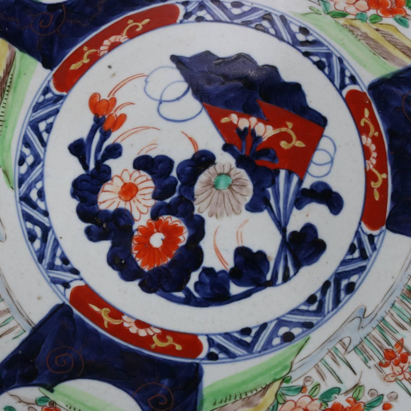 Antique Oriental Japanese Imari Porcelain charger features hand-painted/enameled central floral reserve with surrounding alternating reserves of traditional Asian scenes of herons in the marsh and floral bordering rim, en verso blue