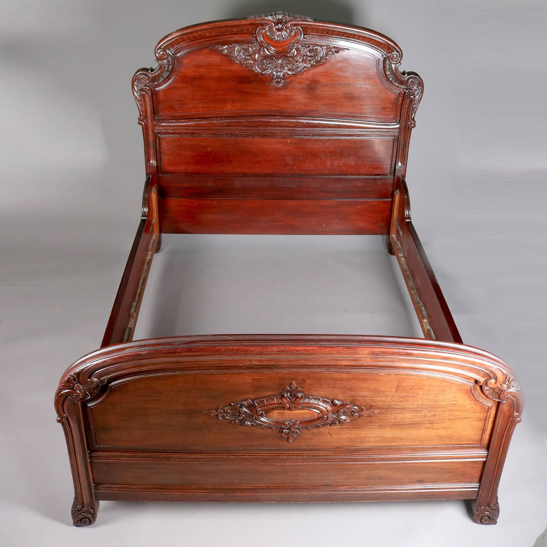 Carved mahogany queen-size bed by Horner Bros, features scroll and foliate decoration including ornately carved crest and acanthus carved feet, with three cross slats, 20th century

Measures: 61