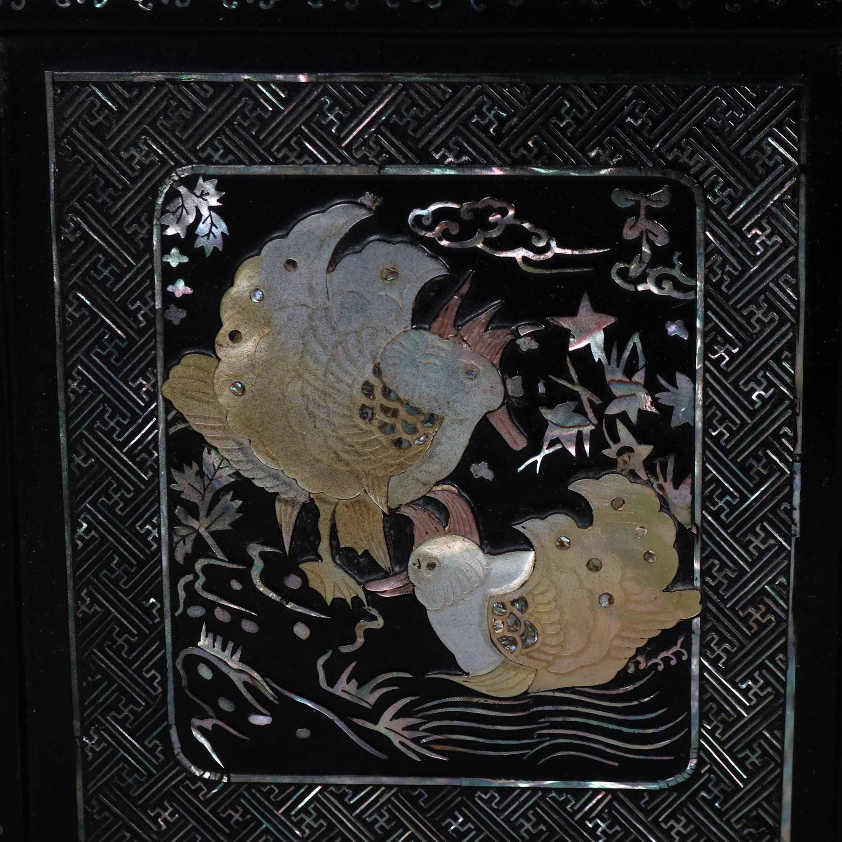 Asian style Chinoiserie table top credenza features ebonized black lacquer finish with mother of pearl inlay in designed panels of bird and animals in landscape settings, two hinged doors open to reveal interior compartment, and four upper drawers,