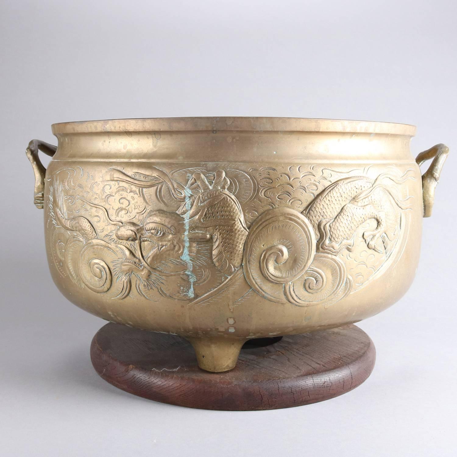 Large antique Japanese Meiji double handled and footed embossed bronze ceremonial cachepot features scene with dragon and tiger, seated on wooded base, 19th century

***DELIVERY NOTICE – Due to COVID-19 we are employing NO-CONTACT PRACTICES in the