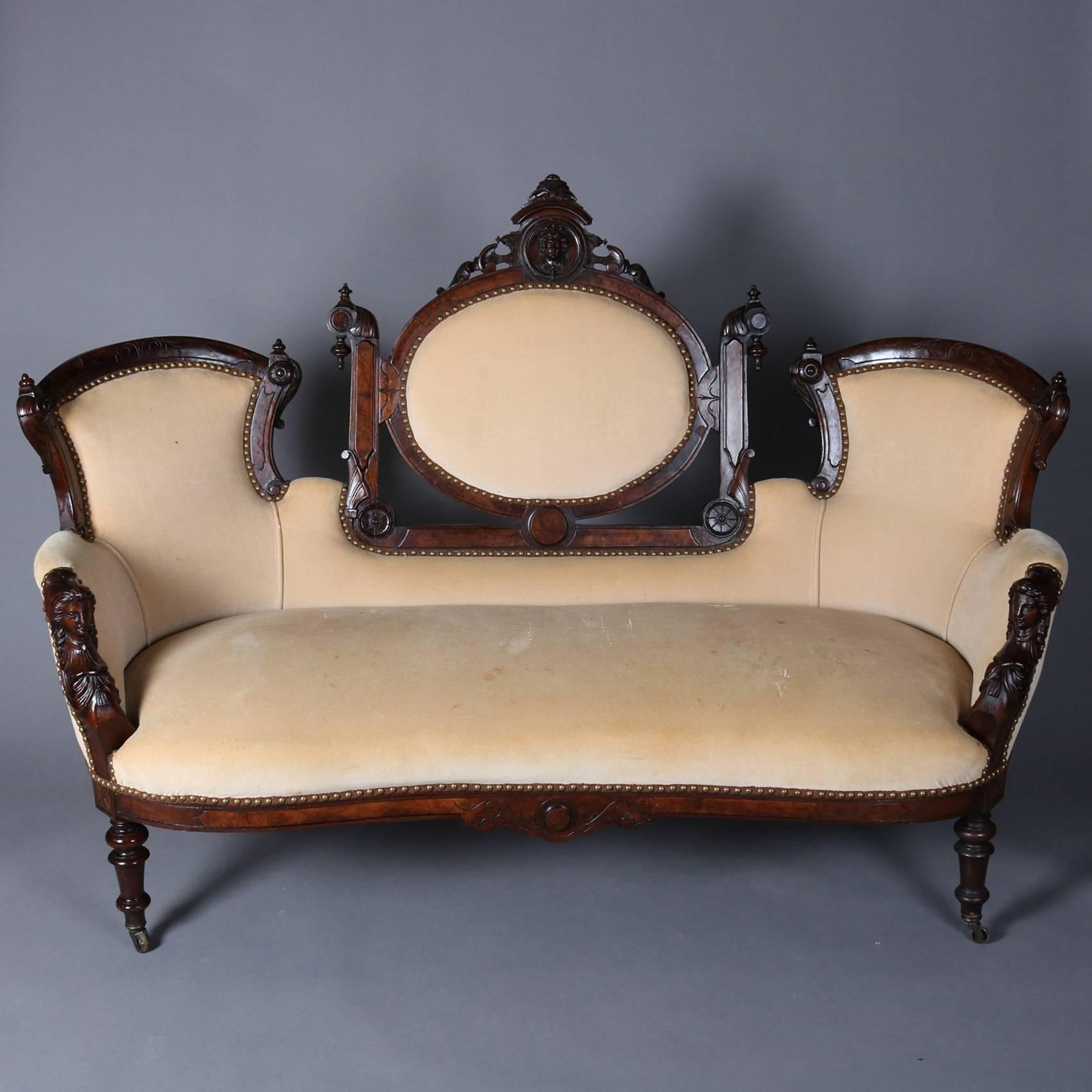 Antique Renaissance Revival three piece parlor set by John Jelliff features figural caved walnut frame with Jenny Lind mask on crests and arms, carved foliate and scroll decoration throughout, sofa with central framed upholstered medallion back and