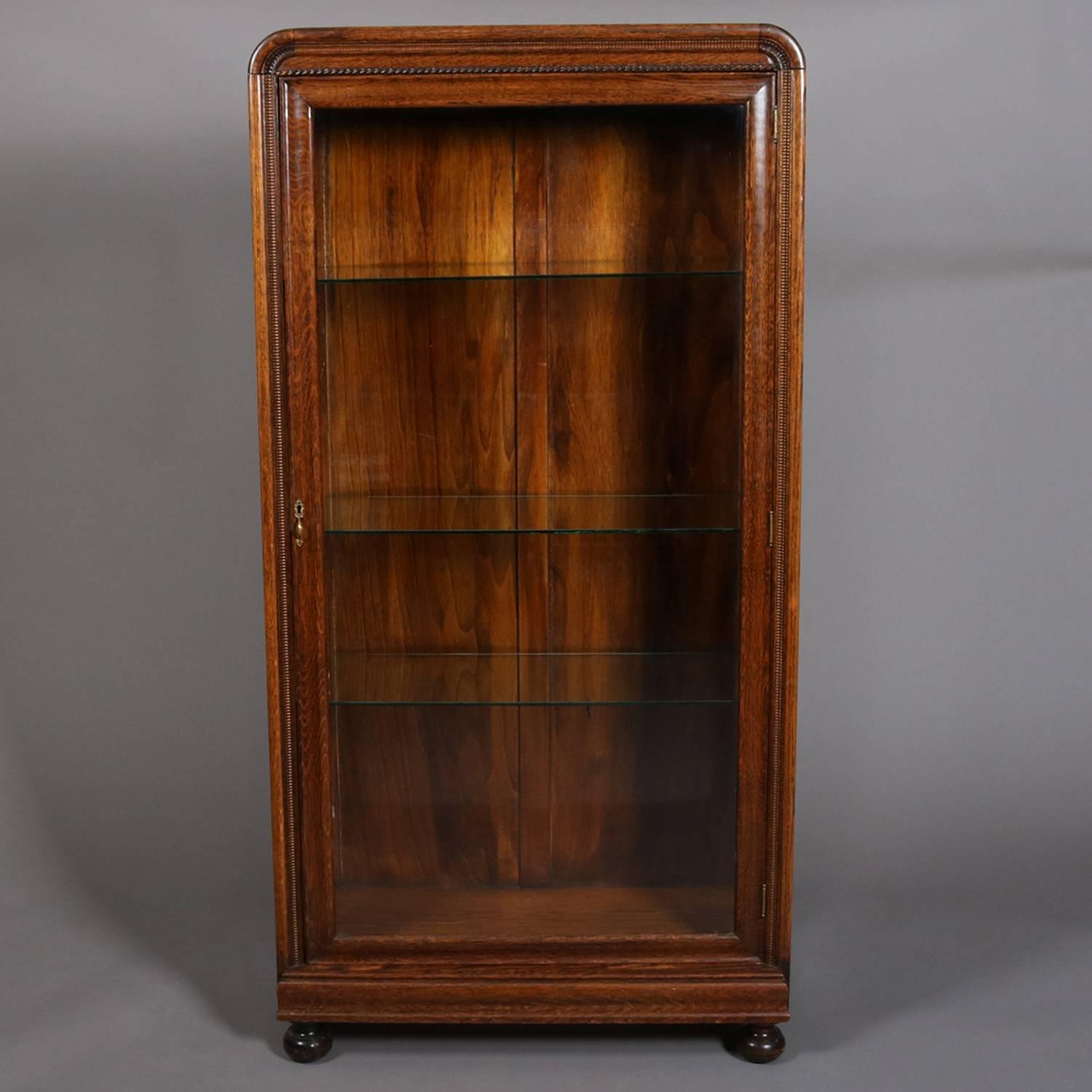 Antique oak display cabinet features single door opening to glass shelved interior and seated on ball feet, 20th century

Measures - 59.5