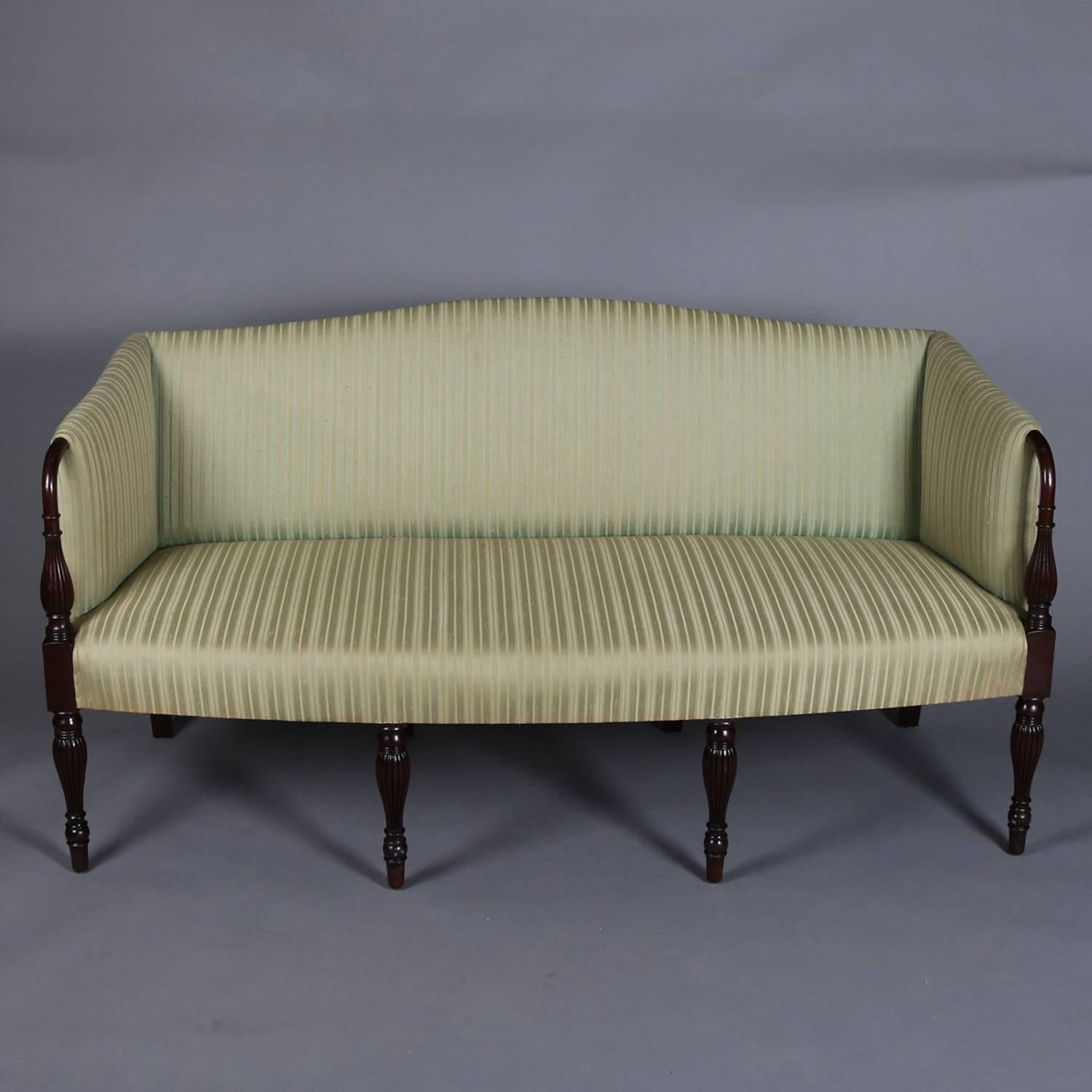 Antique Sheraton sofa features mahogany frame with camel back and seated on four turned legs, upholstered seat, arms and back, 20th century

Measures - 35